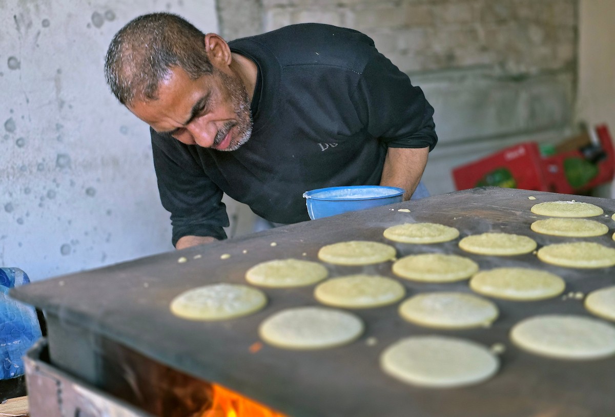 سليم البيوك ُيعدّ معجنات القطايف التقليدية باستخدام أساليب بدائية تعتمد على الحطب والنارمُواصلاً إحياء تقاليد شهر رمضان منذ أكثر من 20 عاماً، في سوق كراج رفح في خان يونس، جنوب قطاع غزة، في 12 فبراير/شباط 2026.تصوير: طارق محمد