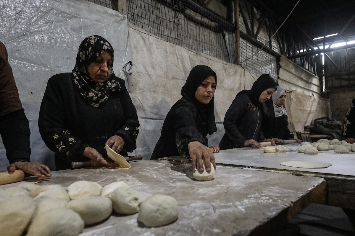 نساء فلسطينيات، زوجات شهداء الحرب، يُجهّزن الخبز لتوزيعه على العائلات النازحة والمحتاجة في مخيم البريج للاجئين وسط قطاع غزة خلال شهر رمضان، في مشهد يُجسّد روح التضامن والصمود في ظلّ الظروف الإنسانية الصعبة، فبراير/شباط 2026. تصوير: معز صالحي