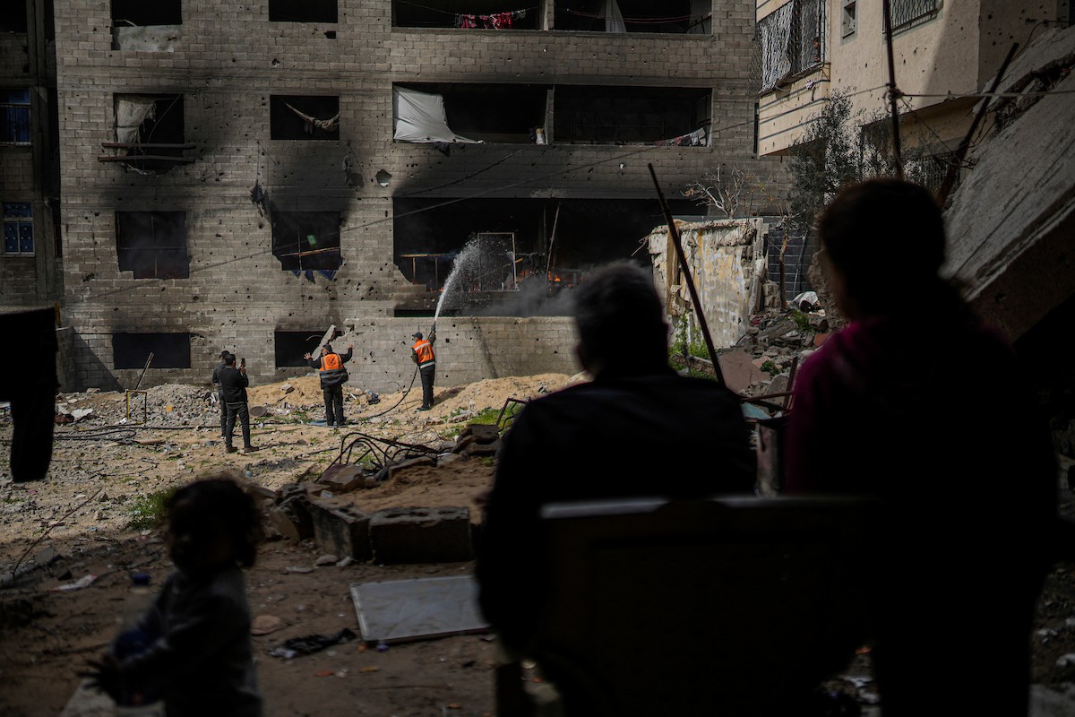 طواقم الدفاع المدني ومتطوعون من المواطنين أثناء محاولة إخماد حريق اندلع في مستودع تابع لمنظمة إغاثة في حي الرمال، غرب مدينة غزة، في 13 فبراير/شباط 2026. صورة: عمر أشتوي