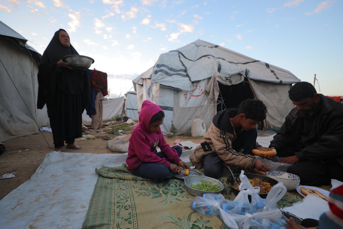 عائلة فلسطينية كفيفة تتناول وجبة الإفطار خارج خيمتها في مخيم بوسط قطاع غزة خلال شهر رمضان