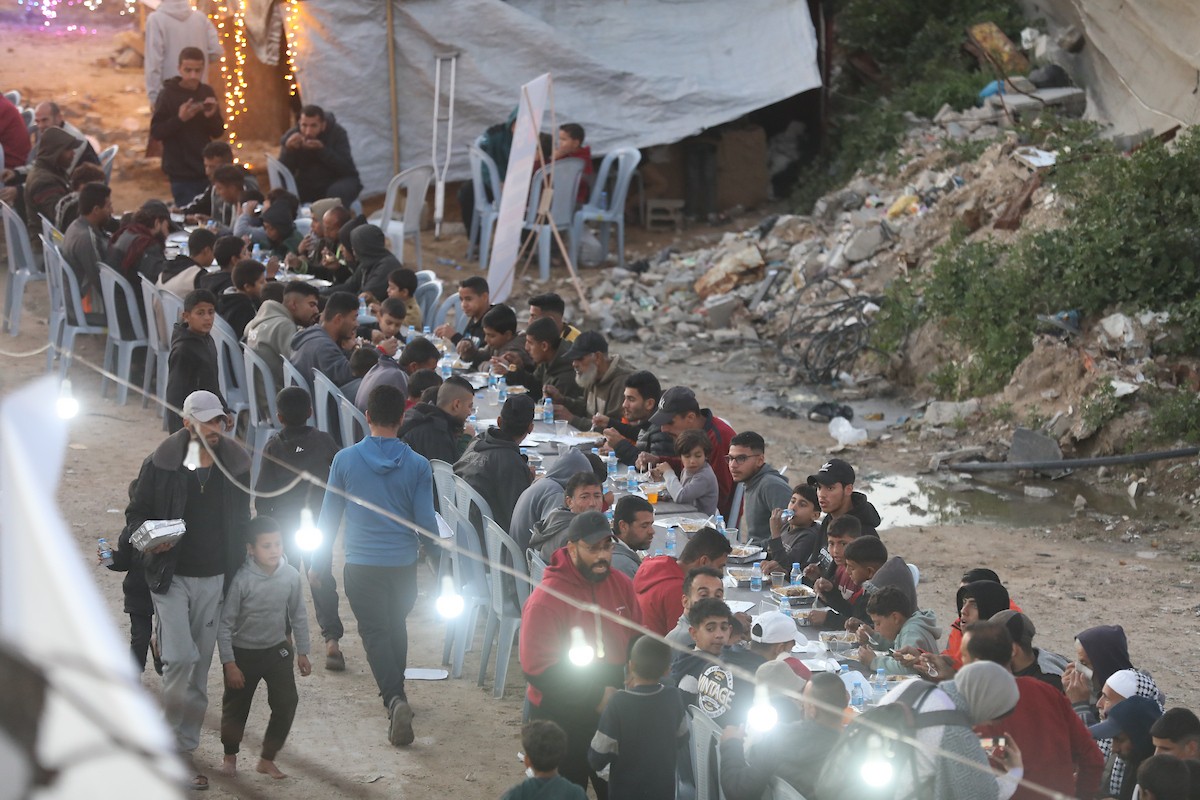 يتجمع فلسطينيون نازحون لتناول وجبة الإفطار وسط أنقاض المباني المدمرة في مدينة غزة، خلال شهر رمضان المبارك، في 25 فبراير/شباط 2026. صورة: عمر أشتوي
