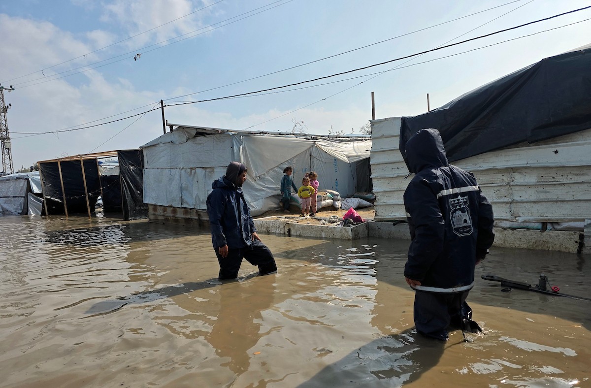 يحاول الفلسطينيون التنقل بعد أن غمرت مياه الأمطار الشوارع وخيام النازحين في خان يونس، جنوب قطاع غزة، في 24 فبراير/شباط 2026. وقد دُمرت البنية التحتية في قطاع غزة على نطاق واسع جراء الحرب والهجمات الإسرائيلية. (صورة: طارق محمد)