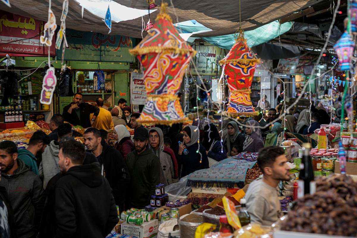 يتسوق الفلسطينيون في أول ليلة من شهر رمضان المبارك في سوق الزاوية، الواقع في قلب مدينة غزة والذي تضرر بشدة جراء الحرب الإسرائيلية. يعرض الباعة بضائعهم على أكشاك مزينة بالفوانيس والأضواء وأطعمة رمضان. مدينة غزة، 17 فبراير/شباط 2026. تصوير: عمر أشتوي