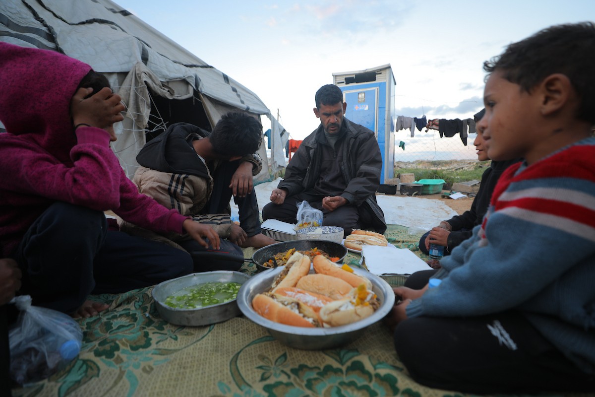 عائلة فلسطينية كفيفة تتناول وجبة الإفطار خارج خيمتها في مخيم بوسط قطاع غزة خلال شهر رمضان