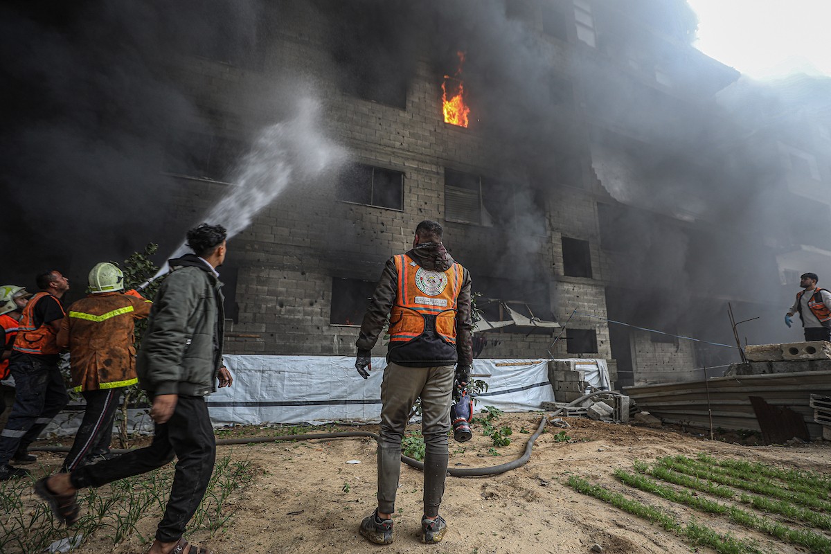 طواقم الدفاع المدني ومتطوعون من المواطنين أثناء محاولة إخماد حريق اندلع في مستودع تابع لمنظمة إغاثة في حي الرمال، غرب مدينة غزة، في 13 فبراير/شباط 2026. صورة: عمر أشتوي