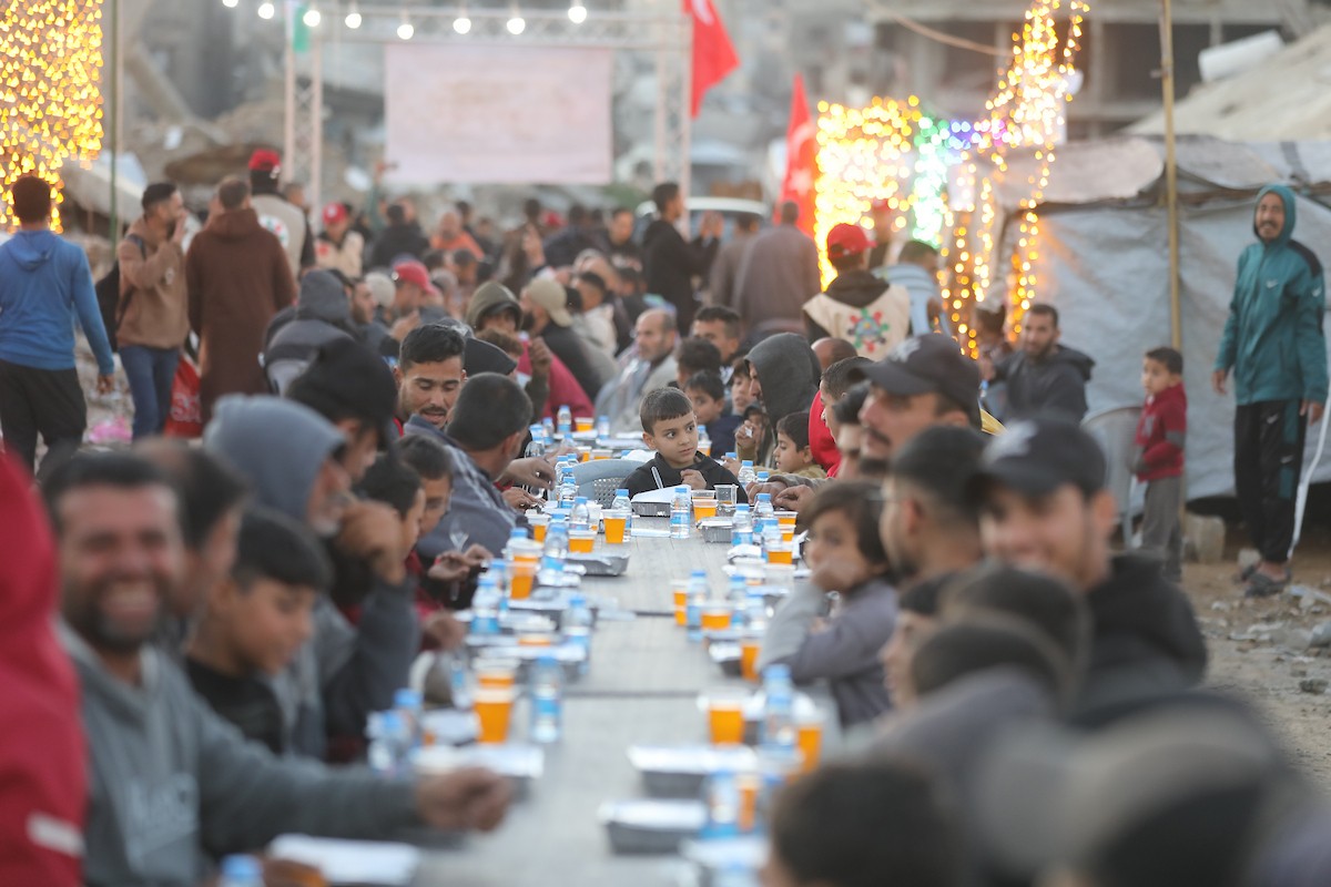 يتجمع فلسطينيون نازحون لتناول وجبة الإفطار وسط أنقاض المباني المدمرة في مدينة غزة، خلال شهر رمضان المبارك، في 25 فبراير/شباط 2026. صورة: عمر أشتوي