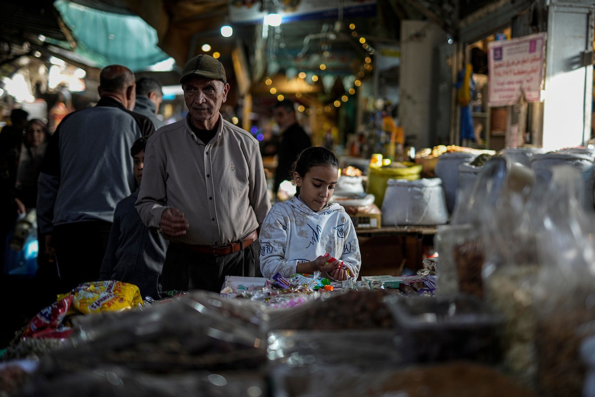 يتسوق الفلسطينيون في أول ليلة من شهر رمضان المبارك في سوق الزاوية، الواقع في قلب مدينة غزة والذي تضرر بشدة جراء الحرب الإسرائيلية. يعرض الباعة بضائعهم على أكشاك مزينة بالفوانيس والأضواء وأطعمة رمضان. مدينة غزة، 17 فبراير/شباط 2026. تصوير: عمر أشتوي