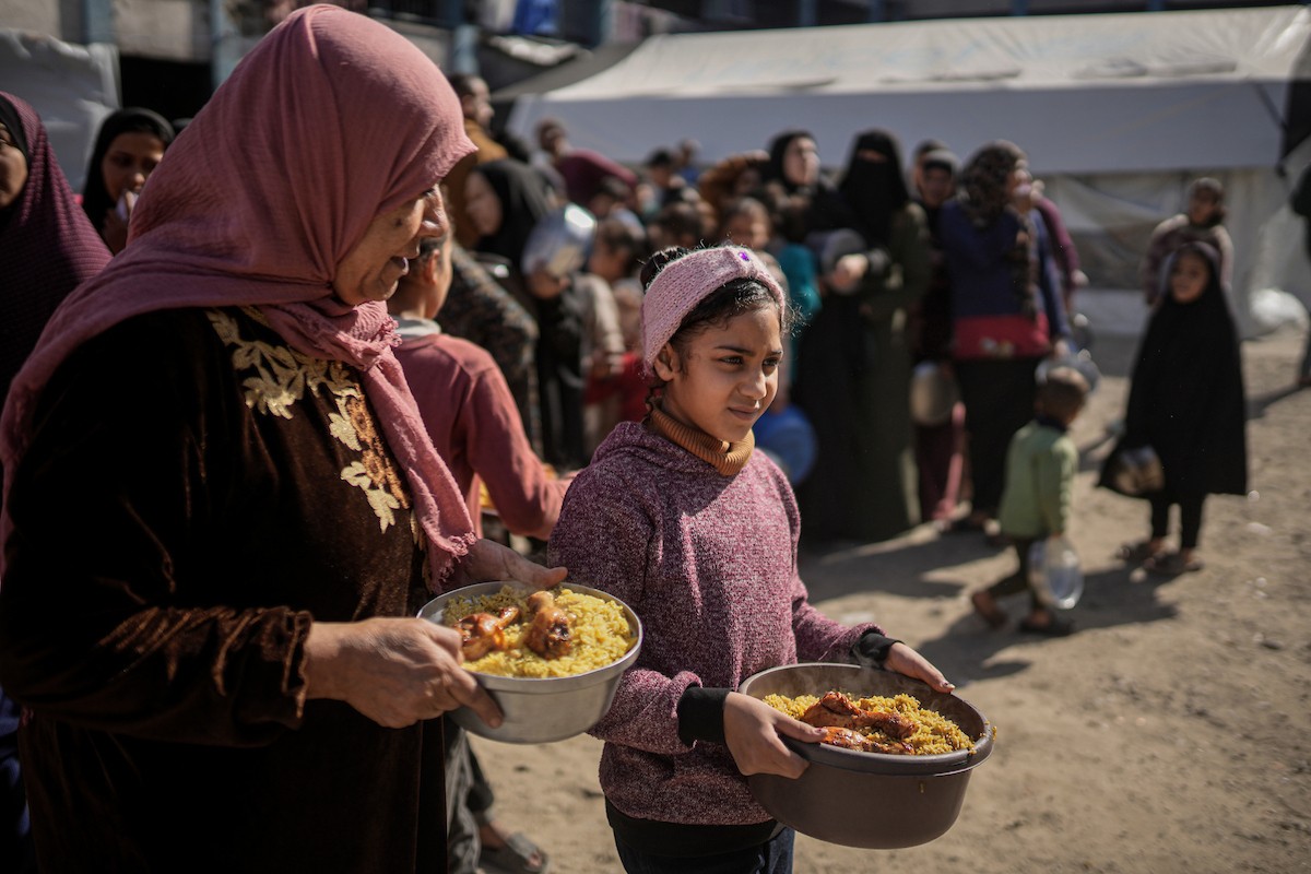 فلسطينيون بينهم أطفال ونساء يتلقون مساعدات غذائية وزعتها منظمات خيرية في أحد مراكز الإيواء بمدينة غزة، وسط أزمة غذائية مستمرة ناجمة عن محدودية المساعدات الإنسانية والظروف الإنسانية المتردية التي يواجهها النازحون، ١٢ فبراير/شباط ٢٠٢٦. تصوير: عمر أشتوي