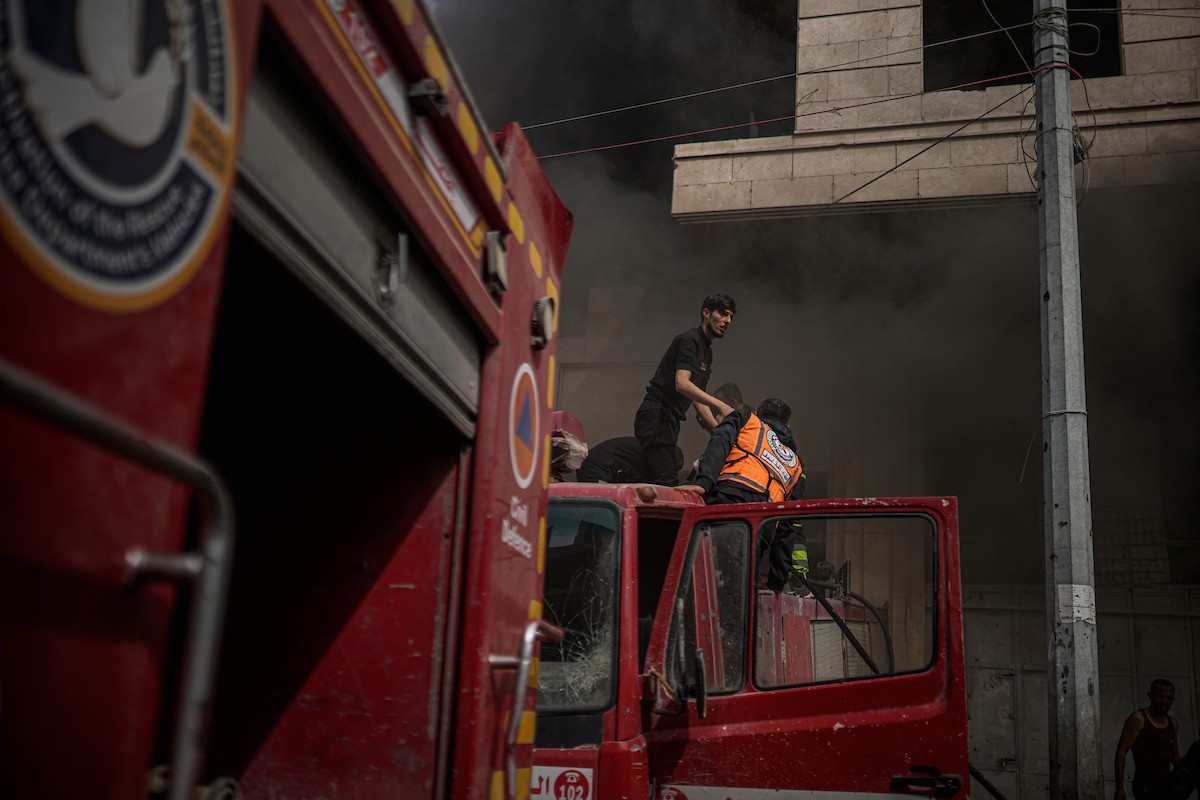 طواقم الدفاع المدني ومتطوعون من المواطنين أثناء محاولة إخماد حريق اندلع في مستودع تابع لمنظمة إغاثة في حي الرمال، غرب مدينة غزة، في 13 فبراير/شباط 2026. صورة: عمر أشتوي