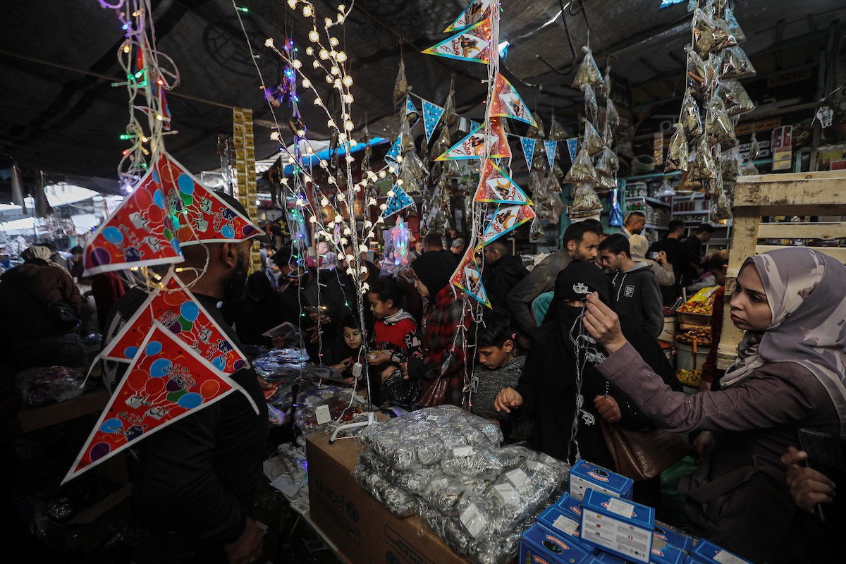 يتسوق الفلسطينيون في أول ليلة من شهر رمضان المبارك في سوق الزاوية، الواقع في قلب مدينة غزة والذي تضرر بشدة جراء الحرب الإسرائيلية. يعرض الباعة بضائعهم على أكشاك مزينة بالفوانيس والأضواء وأطعمة رمضان. مدينة غزة، 17 فبراير/شباط 2026. تصوير: عمر أشتوي