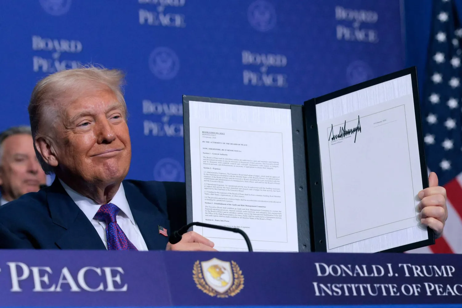 الرئيس الأميركي دونالد ترمب يحمل مذكرة تفاهم وقع عليها خلال اجتماع «مجلس السلام» في واشنطن الخميس (أ.ف.ب).webp