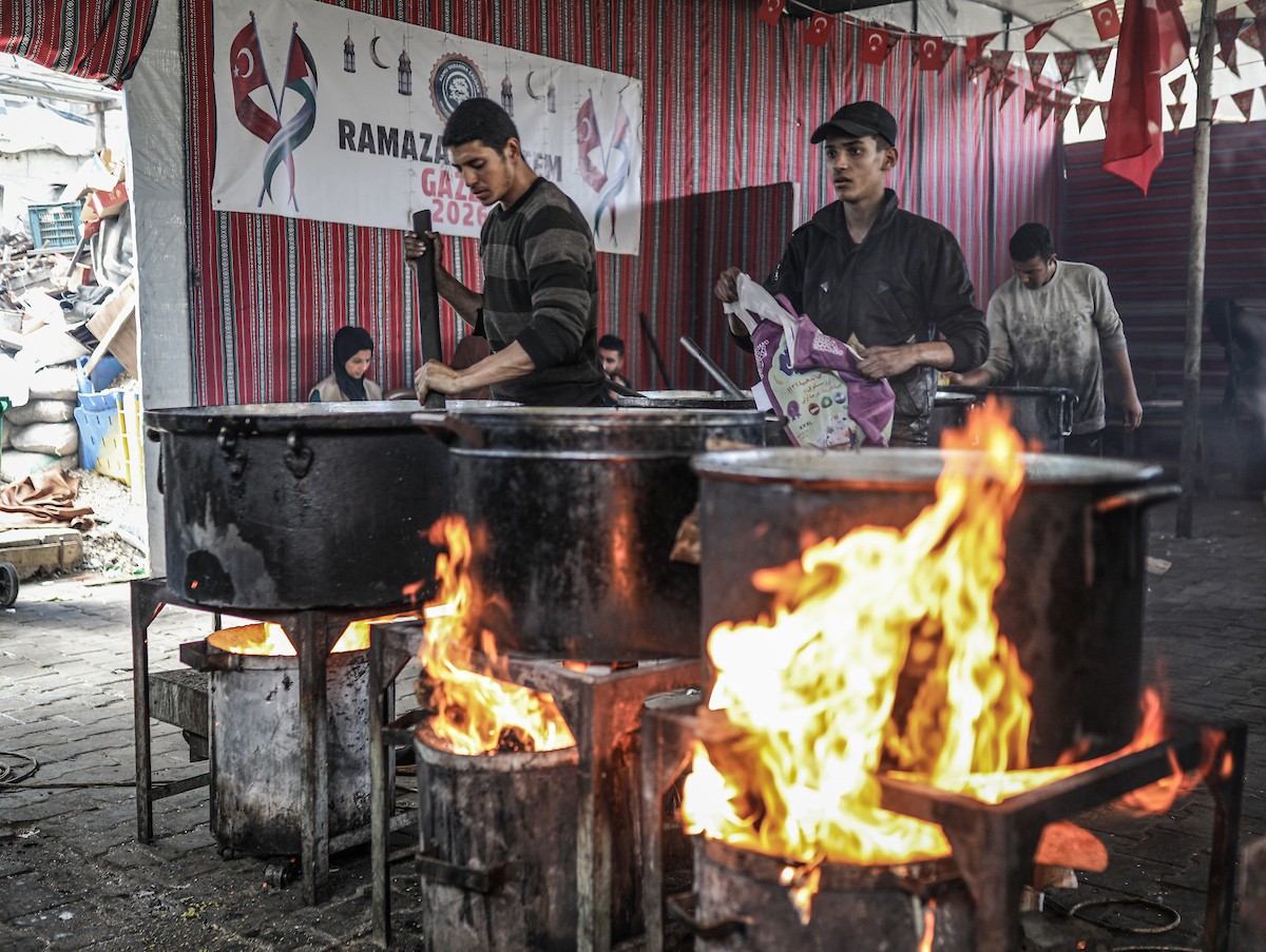 يتجمع فلسطينيون نازحون لتناول وجبة إفطارهم الرمضانية في مطبخ خيري بمخيم النصيرات للاجئين وسط قطاع غزة، في 24 فبراير/شباط 2026. ويواجه النازحون ظروفًا معيشية قاسية نتيجة انعدام الدخل ونقص المساعدات الإنسانية. (صورة: رمزي أبو عامر / apaimages)