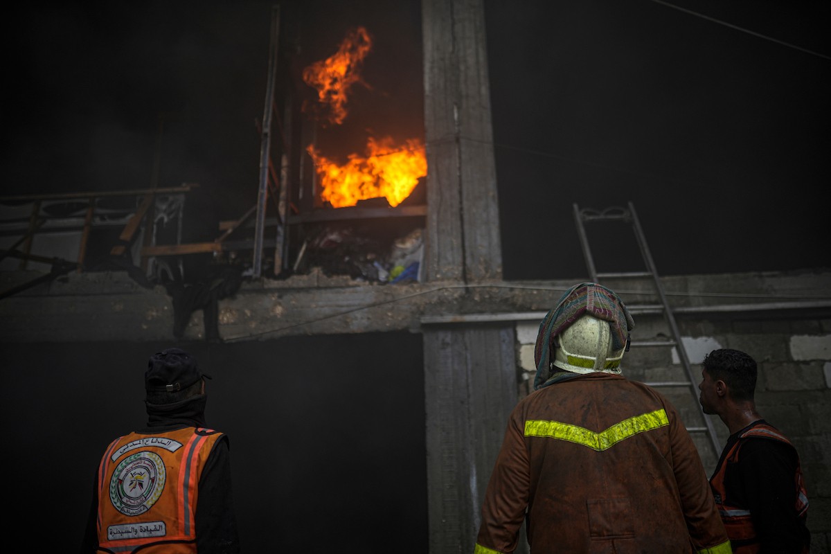 طواقم الدفاع المدني ومتطوعون من المواطنين أثناء محاولة إخماد حريق اندلع في مستودع تابع لمنظمة إغاثة في حي الرمال، غرب مدينة غزة، في 13 فبراير/شباط 2026. صورة: عمر أشتوي