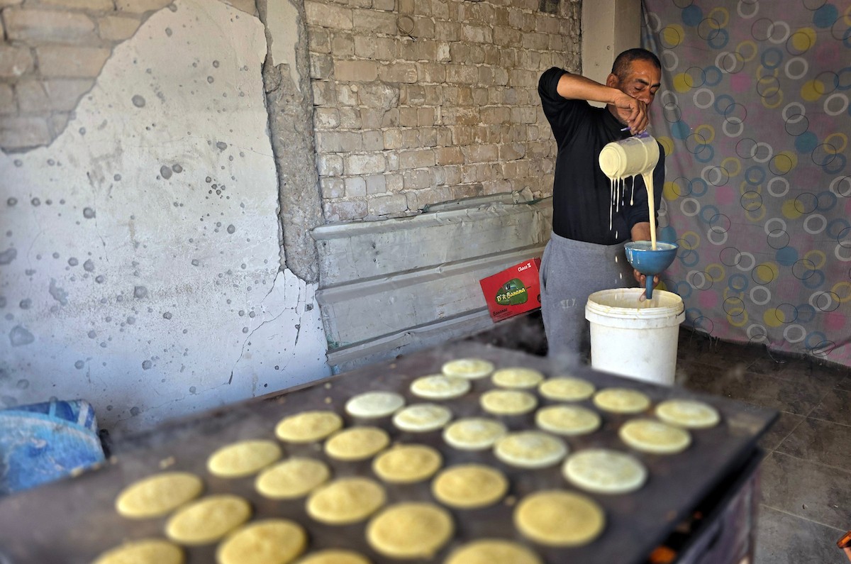 سليم البيوك ُيعدّ معجنات القطايف التقليدية باستخدام أساليب بدائية تعتمد على الحطب والنارمُواصلاً إحياء تقاليد شهر رمضان منذ أكثر من 20 عاماً، في سوق كراج رفح في خان يونس، جنوب قطاع غزة، في 12 فبراير/شباط 2026.تصوير: طارق محمد