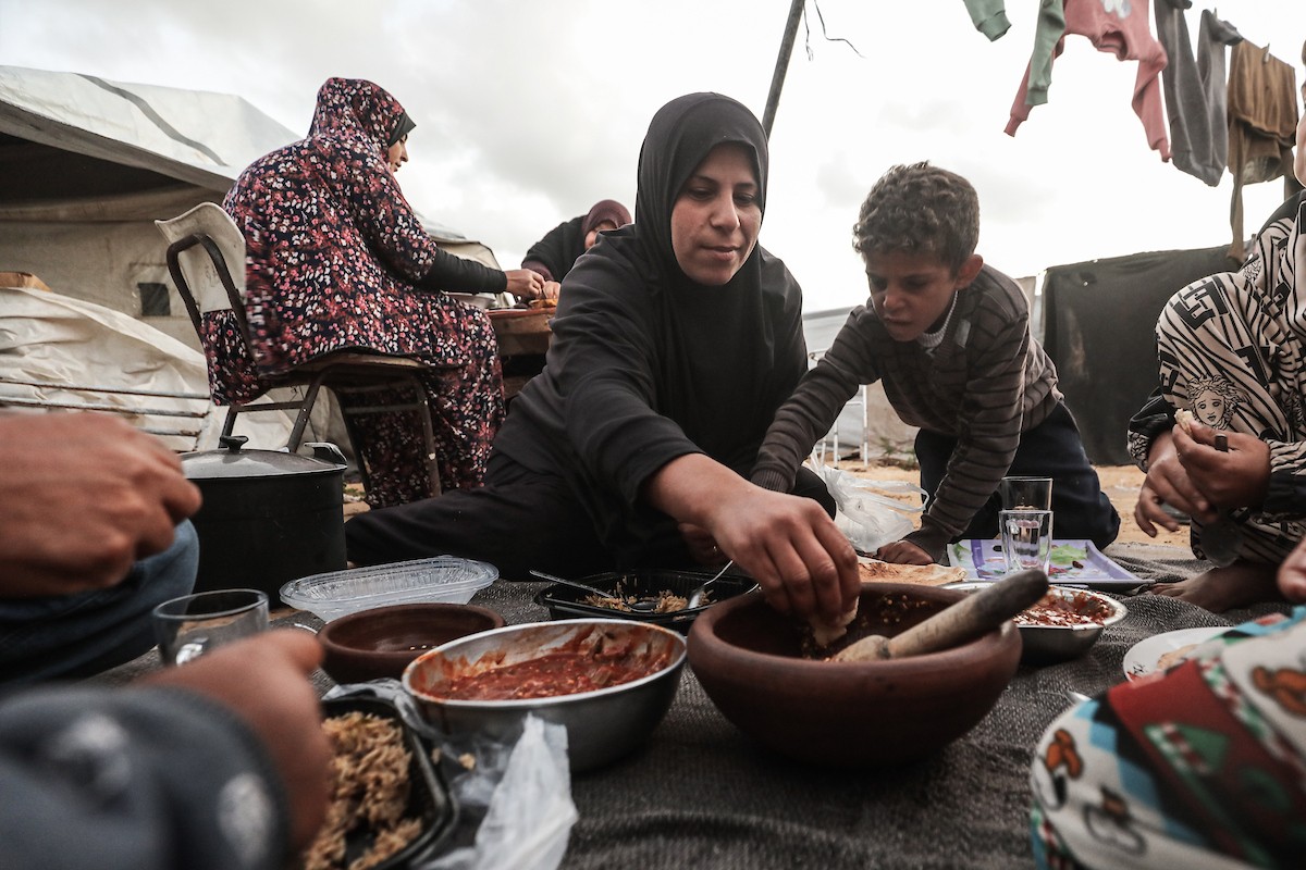 عائلة فلسطينية نازحة تتناول فطورها خلال شهر رمضان داخل خيمة متداعية في مخيم النصيرات للاجئين وسط قطاع غزة. تواجه العائلات النازحة ظروفًا معيشية قاسية نتيجة الحرب، مع انعدام الدخل ونقص حاد في المساعدات الإنسانية، 26 فبراير/شباط 2026. تصوير: معز صالحي