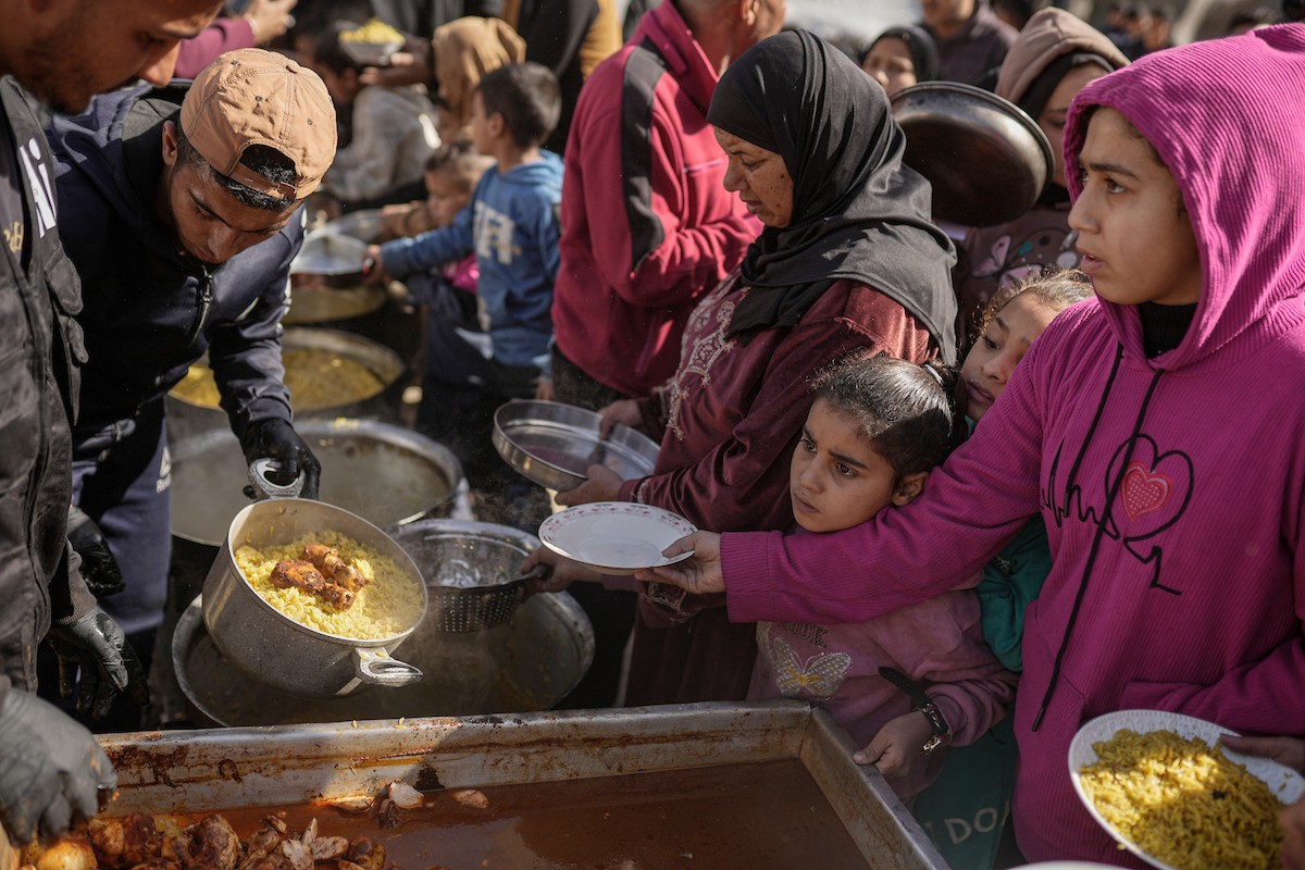 فلسطينيون بينهم أطفال ونساء يتلقون مساعدات غذائية وزعتها منظمات خيرية في أحد مراكز الإيواء بمدينة غزة، وسط أزمة غذائية مستمرة ناجمة عن محدودية المساعدات الإنسانية والظروف الإنسانية المتردية التي يواجهها النازحون، ١٢ فبراير/شباط ٢٠٢٦. تصوير: عمر أشتوي
