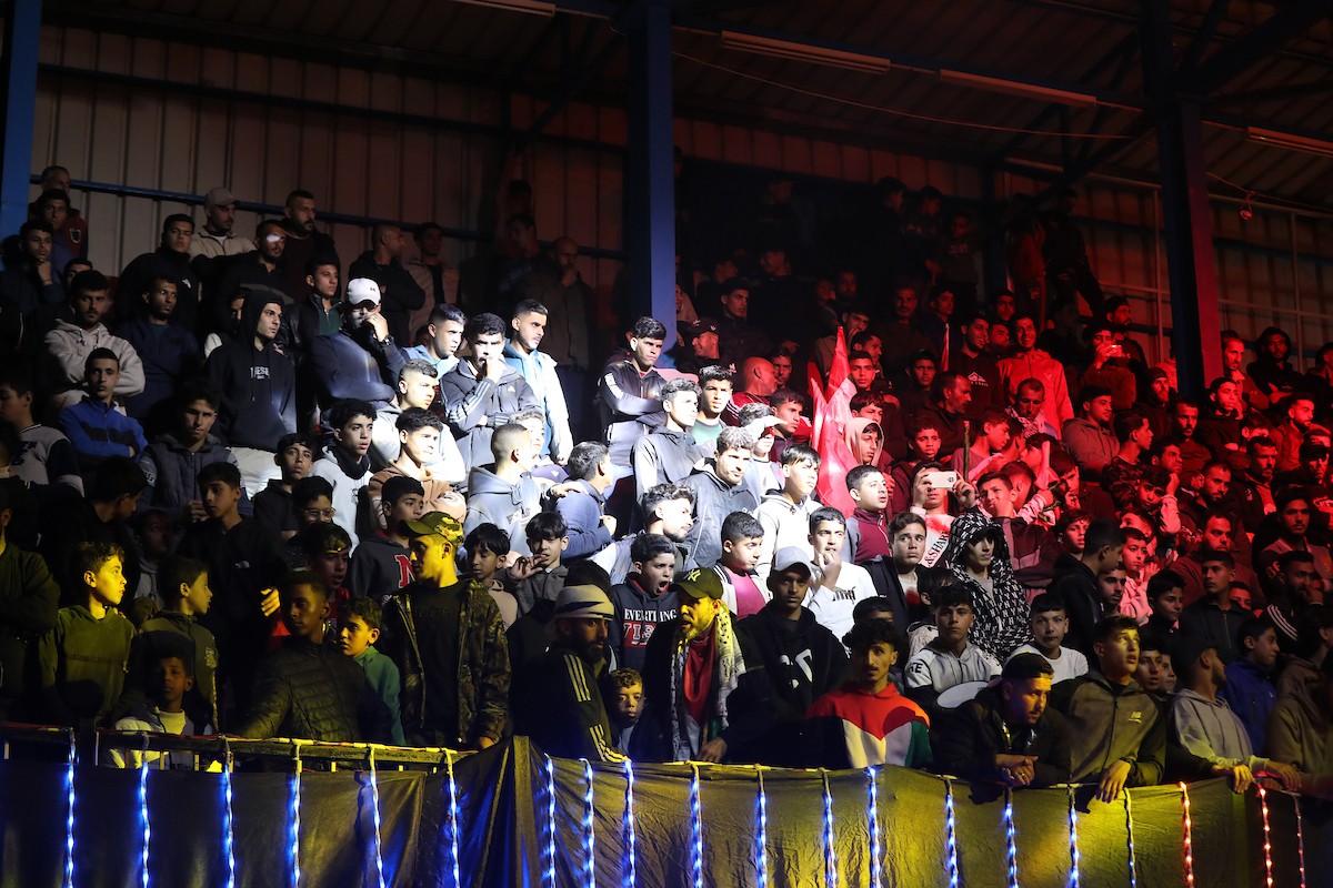 لاعبون فلسطينيون من فريقي النصيرات ورفح يتنافسون خلال مباراة كرة قدم على ملعب نادي خدمات النصيرات، ضمن بطولة غزة الرمضانية، بحضور حشد جماهيري كبير، في مخيم النصيرات بوسط قطاع غزة، بتاريخ 21 فبراير/شباط 2026. تصوير: معز صالحي / apaimages