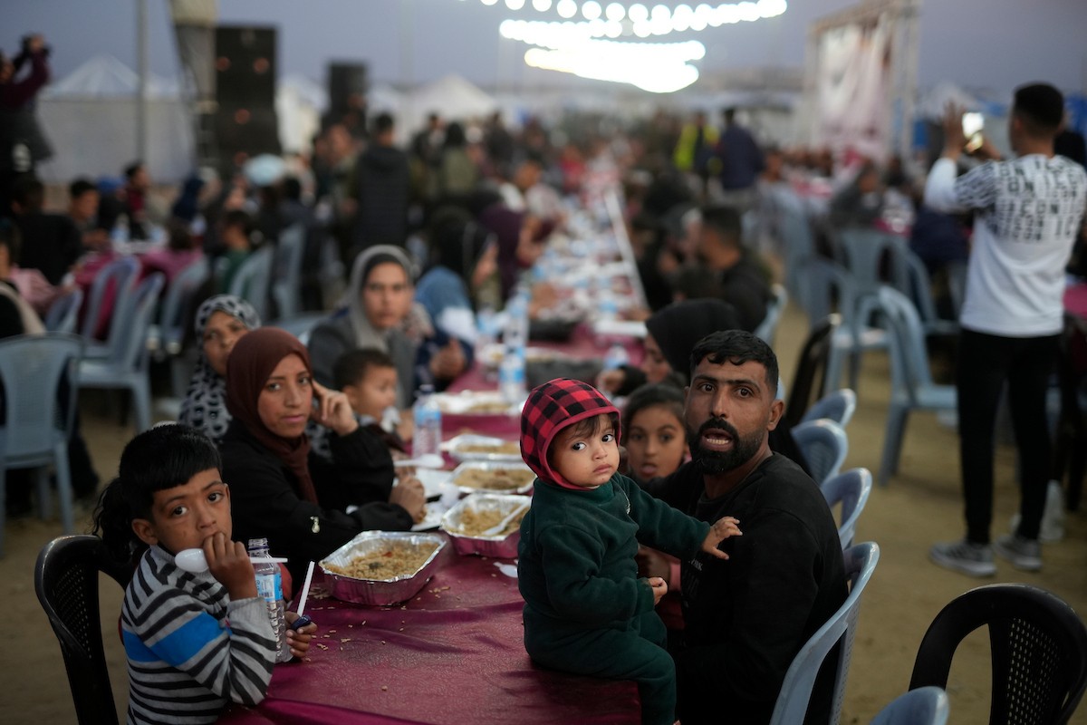 يتجمع فلسطينيون نازحون لتناول وجبة الإفطار، وهي وجبة كسر الصيام، خلال شهر رمضان المبارك في مخيم خيام يؤويهم، بحي الزهراء وسط قطاع غزة، يوم السبت 21 فبراير/شباط 2026. تصوير: عمر أشتوي