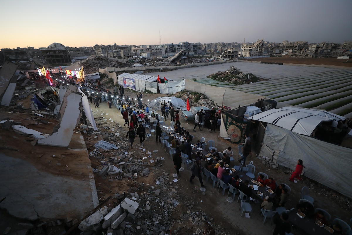 يتجمع فلسطينيون نازحون لتناول وجبة الإفطار وسط أنقاض المباني المدمرة في مدينة غزة، خلال شهر رمضان المبارك، في 25 فبراير/شباط 2026. صورة: عمر أشتوي