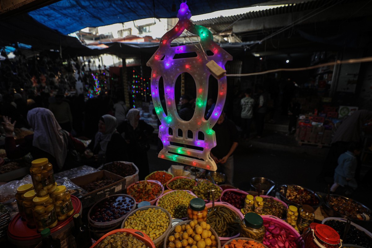 يتسوق الفلسطينيون في أول ليلة من شهر رمضان المبارك في سوق الزاوية، الواقع في قلب مدينة غزة والذي تضرر بشدة جراء الحرب الإسرائيلية. يعرض الباعة بضائعهم على أكشاك مزينة بالفوانيس والأضواء وأطعمة رمضان. مدينة غزة، 17 فبراير/شباط 2026. تصوير: عمر أشتوي