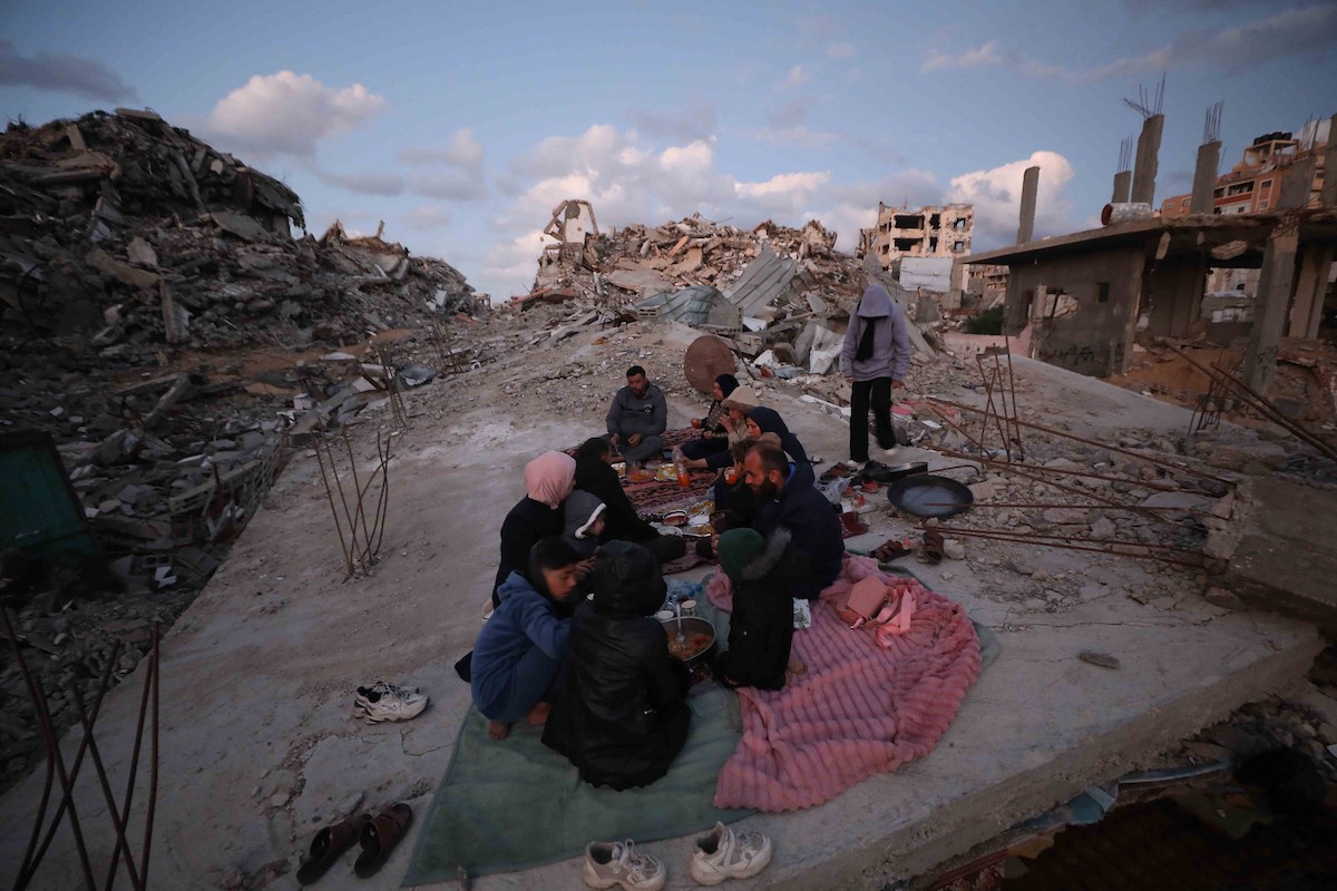 عائلة فلسطينية تتناول إفطارها خلال شهر رمضان على سطح منزلها الذي دمره قصف جوي إسرائيلي خلال حرب غزة في 27 فبراير/شباط 2026. صورة: عمر أشتوي