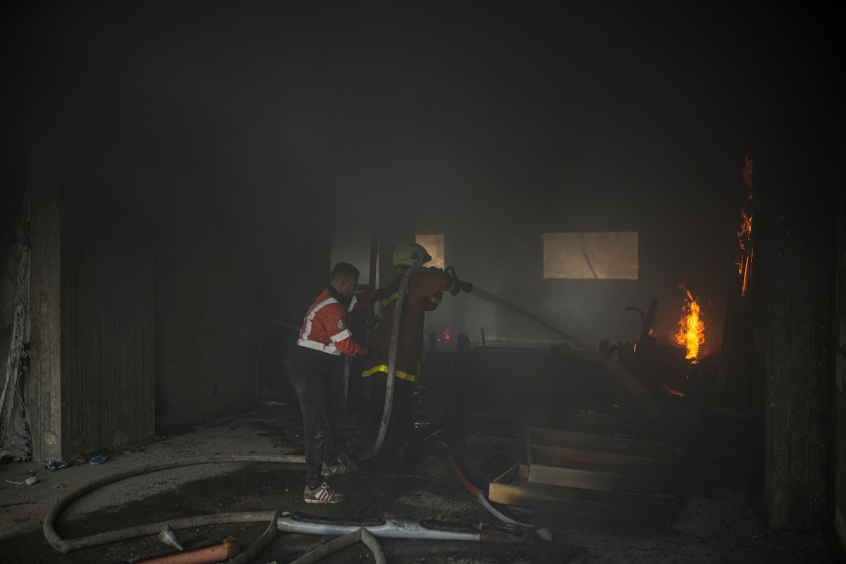 طواقم الدفاع المدني ومتطوعون من المواطنين أثناء محاولة إخماد حريق اندلع في مستودع تابع لمنظمة إغاثة في حي الرمال، غرب مدينة غزة، في 13 فبراير/شباط 2026. صورة: عمر أشتوي