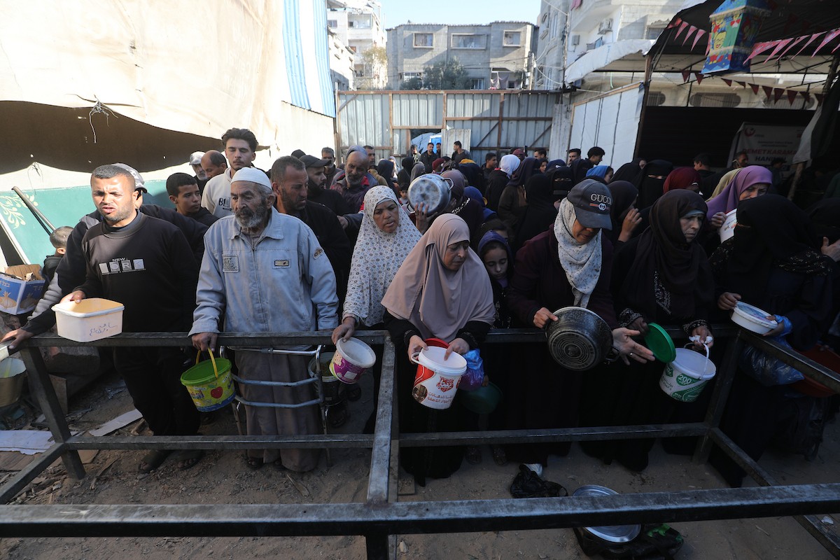 يتجمع فلسطينيون لتناول وجبة ساخنة وزعتها إحدى الجمعيات الخيرية، وسط أزمة غذائية مستمرة بسبب محدودية المساعدات الإنسانية خلال شهر رمضان في مخيم النصيرات للاجئين وسط قطاع غزة. ٢٣ فبرايرشباط ٢٠٢٦. تصوير معز صالحي