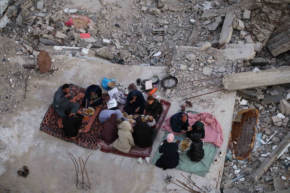 عائلة فلسطينية تتناول إفطارها خلال شهر رمضان على سطح منزلها الذي دمره قصف جوي إسرائيلي خلال حرب غزة في 27 فبراير/شباط 2026. صورة: عمر أشتوي