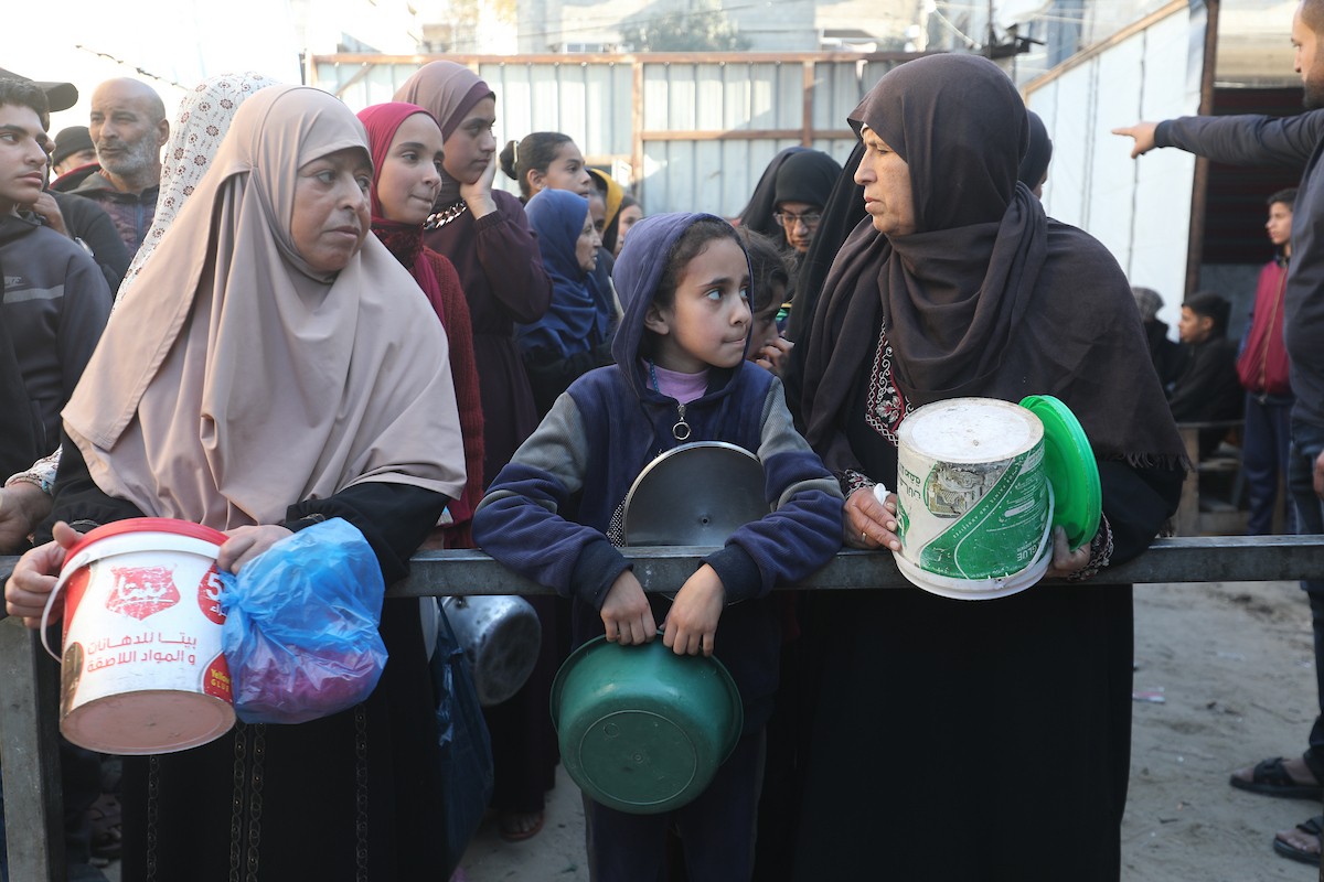 يتجمع فلسطينيون لتناول وجبة ساخنة وزعتها إحدى الجمعيات الخيرية، وسط أزمة غذائية مستمرة بسبب محدودية المساعدات الإنسانية خلال شهر رمضان في مخيم النصيرات للاجئين وسط قطاع غزة. ٢٣ فبرايرشباط ٢٠٢٦. تصوير معز صالحي