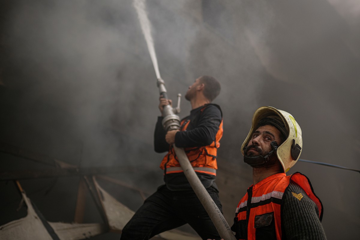 طواقم الدفاع المدني ومتطوعون من المواطنين أثناء محاولة إخماد حريق اندلع في مستودع تابع لمنظمة إغاثة في حي الرمال، غرب مدينة غزة، في 13 فبراير/شباط 2026. صورة: عمر أشتوي