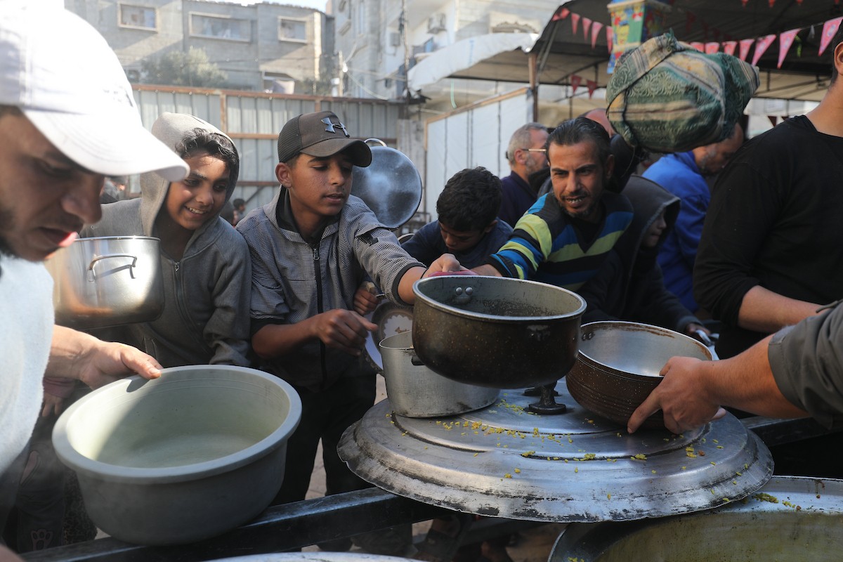 يتجمع فلسطينيون لتناول وجبة ساخنة وزعتها إحدى الجمعيات الخيرية، وسط أزمة غذائية مستمرة بسبب محدودية المساعدات الإنسانية خلال شهر رمضان في مخيم النصيرات للاجئين وسط قطاع غزة. ٢٣ فبرايرشباط ٢٠٢٦. تصوير معز صالحي