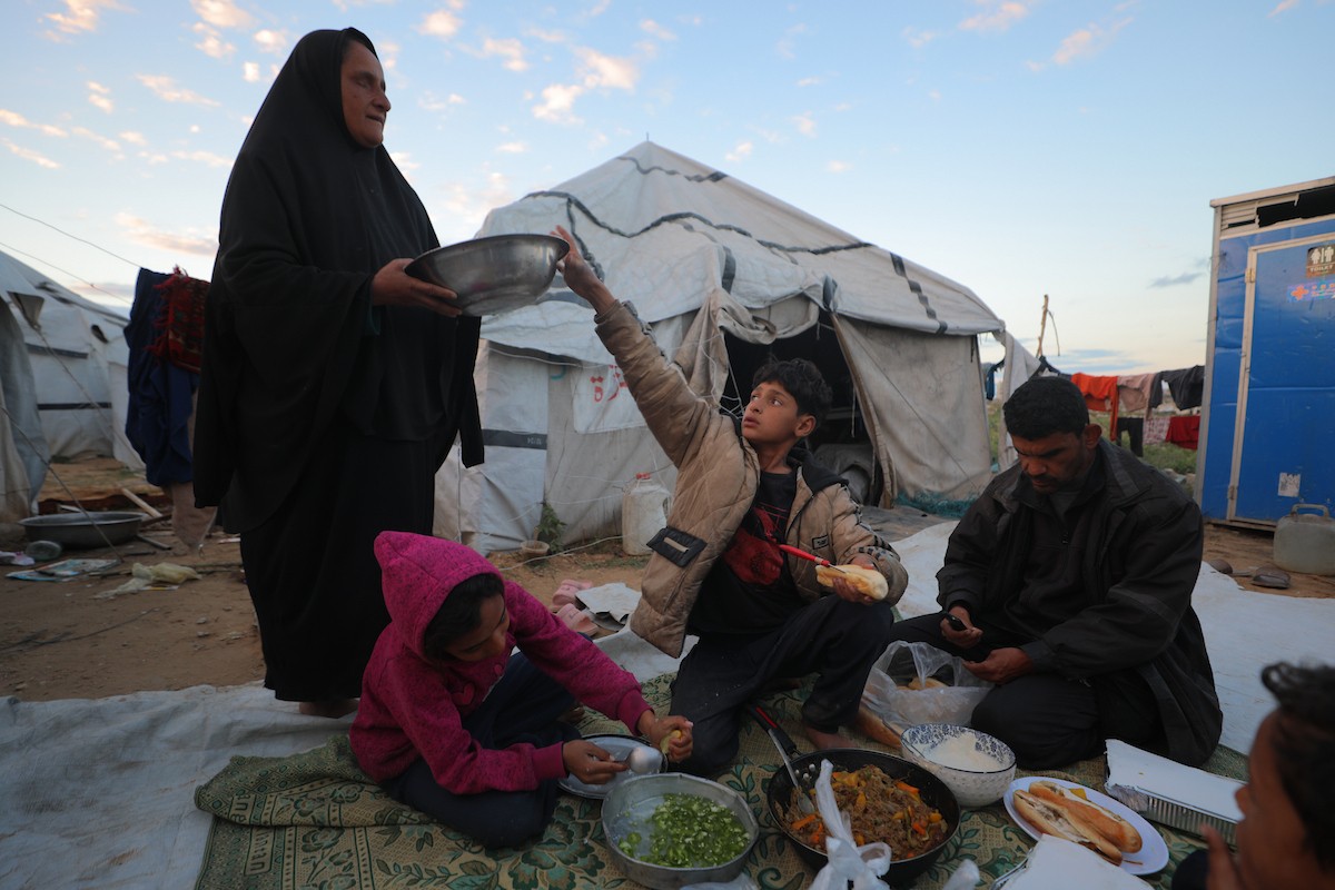 عائلة فلسطينية كفيفة تتناول وجبة الإفطار خارج خيمتها في مخيم بوسط قطاع غزة خلال شهر رمضان