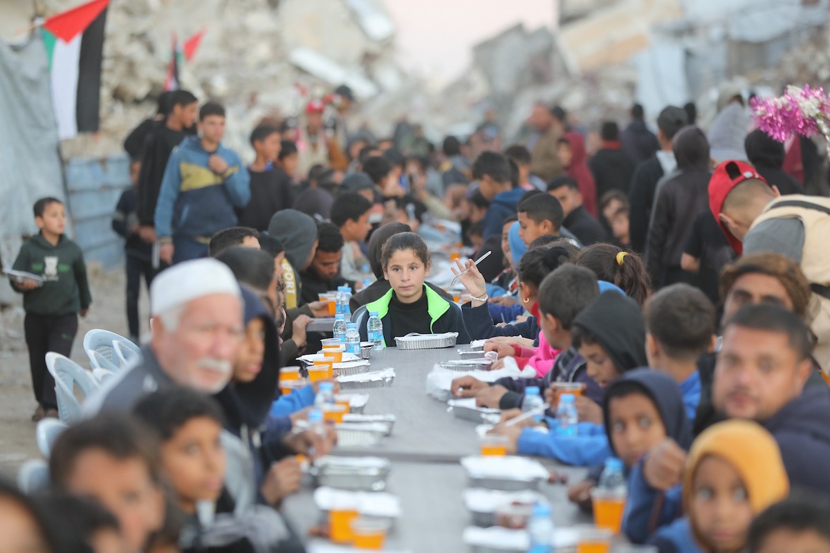 يتجمع فلسطينيون نازحون لتناول وجبة الإفطار وسط أنقاض المباني المدمرة في مدينة غزة، خلال شهر رمضان المبارك، في 25 فبراير/شباط 2026. صورة: عمر أشتوي