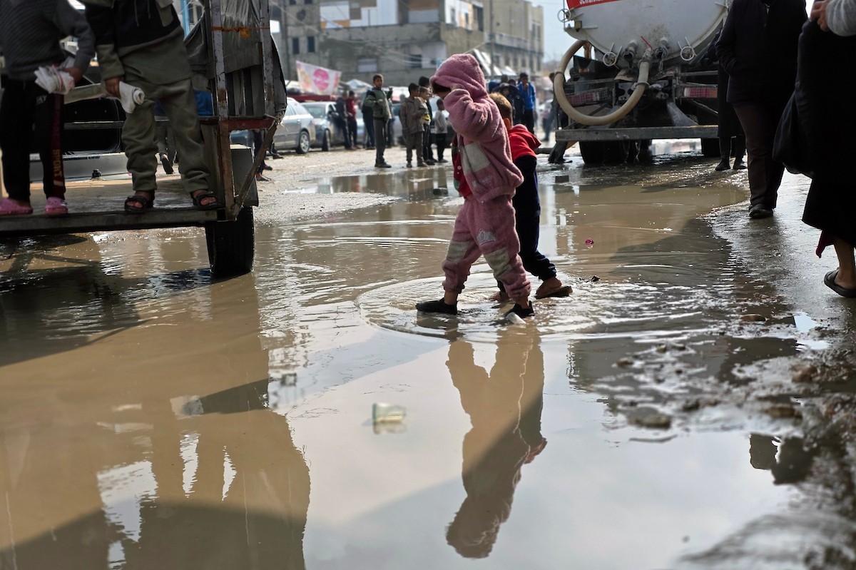 يحاول الفلسطينيون التنقل بعد أن غمرت مياه الأمطار الشوارع وخيام النازحين في خان يونس، جنوب قطاع غزة، في 24 فبراير/شباط 2026. وقد دُمرت البنية التحتية في قطاع غزة على نطاق واسع جراء الحرب والهجمات الإسرائيلية. (صورة: طارق محمد)