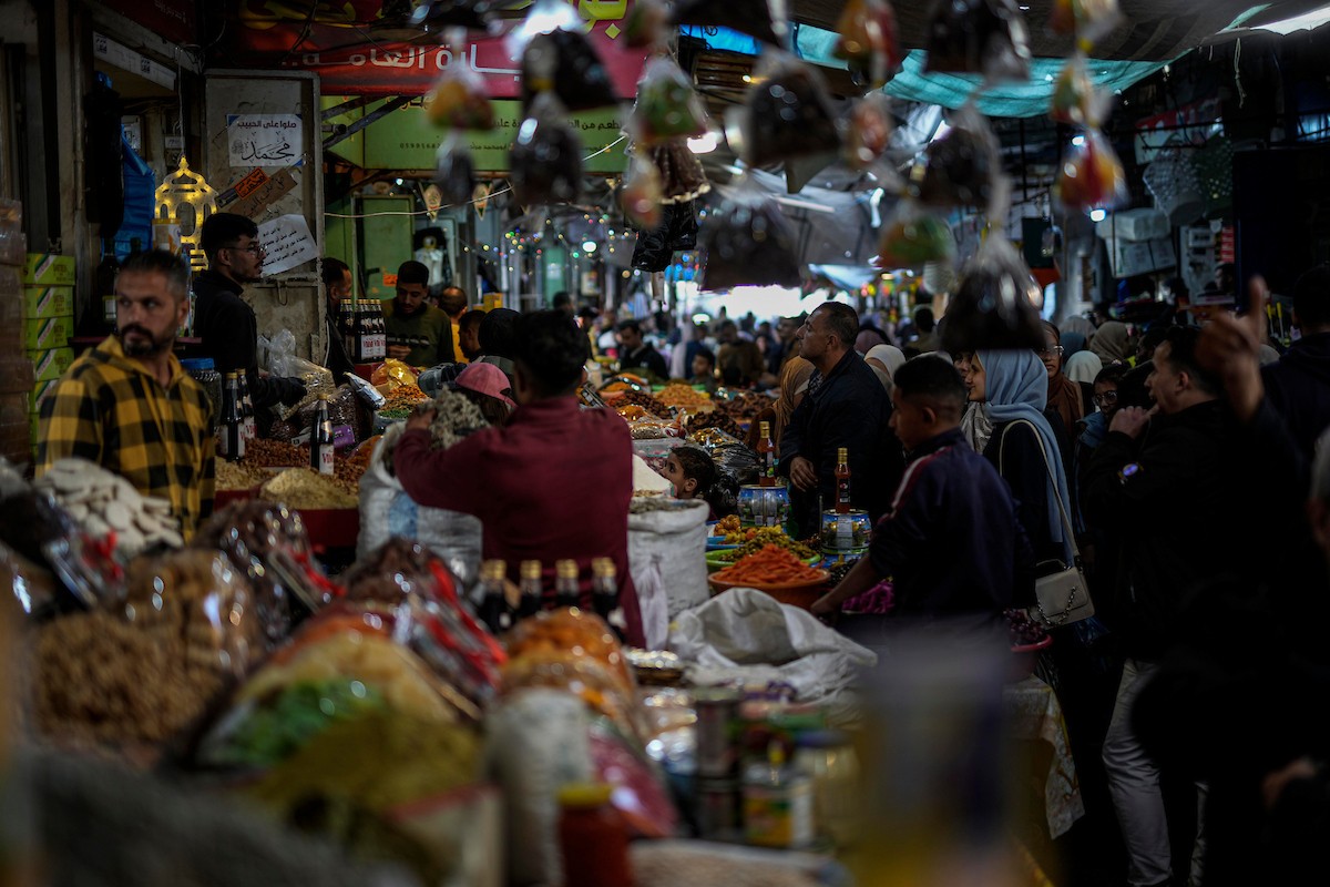 يتسوق الفلسطينيون في أول ليلة من شهر رمضان المبارك في سوق الزاوية، الواقع في قلب مدينة غزة والذي تضرر بشدة جراء الحرب الإسرائيلية. يعرض الباعة بضائعهم على أكشاك مزينة بالفوانيس والأضواء وأطعمة رمضان. مدينة غزة، 17 فبراير/شباط 2026. تصوير: عمر أشتوي