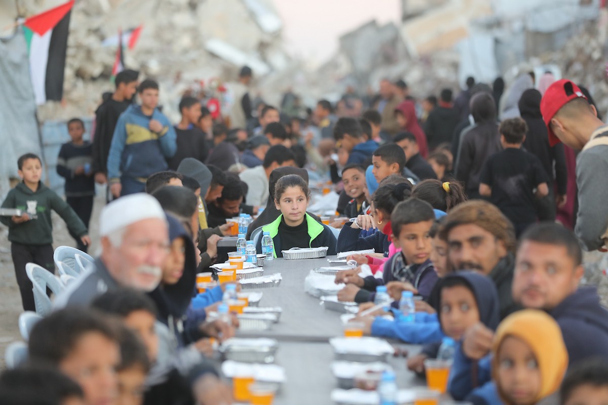 يتجمع فلسطينيون نازحون لتناول وجبة الإفطار وسط أنقاض المباني المدمرة في مدينة غزة، خلال شهر رمضان المبارك، في 25 فبراير/شباط 2026. صورة: عمر أشتوي