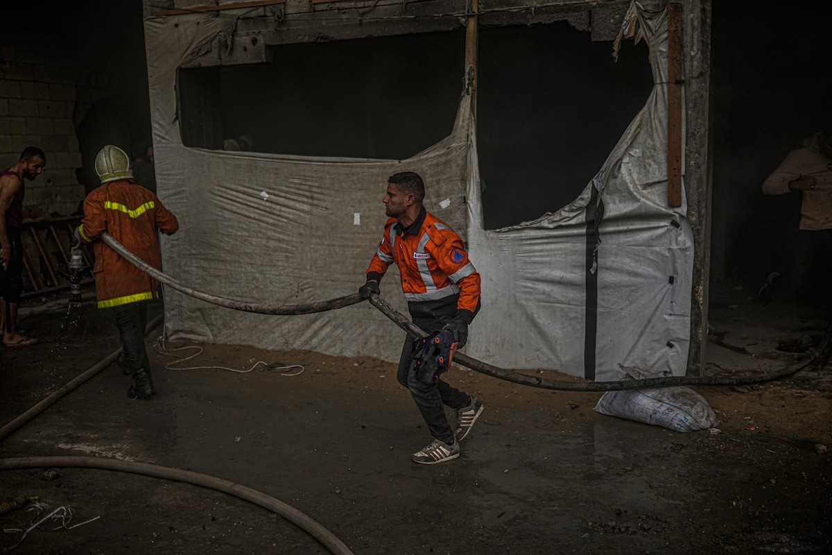 طواقم الدفاع المدني ومتطوعون من المواطنين أثناء محاولة إخماد حريق اندلع في مستودع تابع لمنظمة إغاثة في حي الرمال، غرب مدينة غزة، في 13 فبراير/شباط 2026. صورة: عمر أشتوي