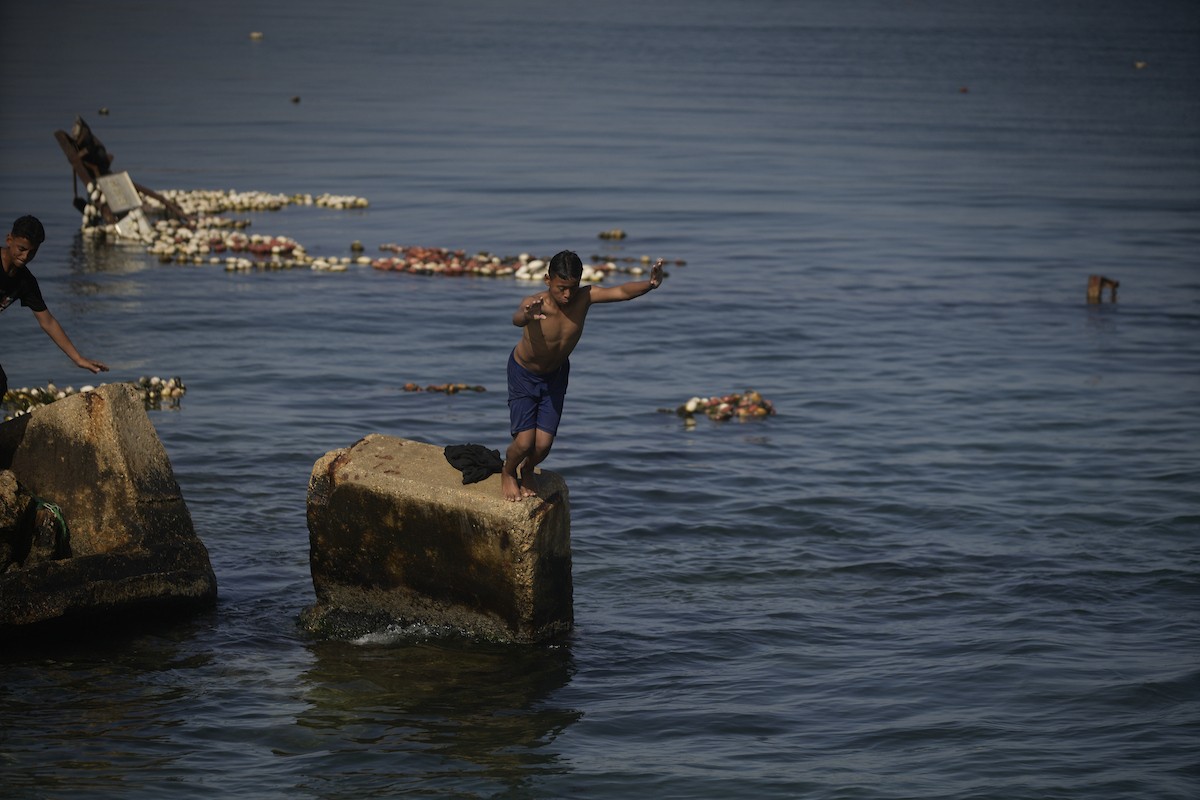 يسبح أطفال قرب ميناء غزة المدمر، في مشهد يعكس تمسكهم بلحظات الفرح رغم الدمار المحيط بهم. يُعدّ البحر في غزة المتنفس الوحيد لسكانها الذين يواجهون آثار الحرب والنزوح، والذين يعيشون في خيام تفتقر لأبسط مقومات الحياة، ١٢ فبراير ٢٠٢٦. تصوير: عمر أشتوي