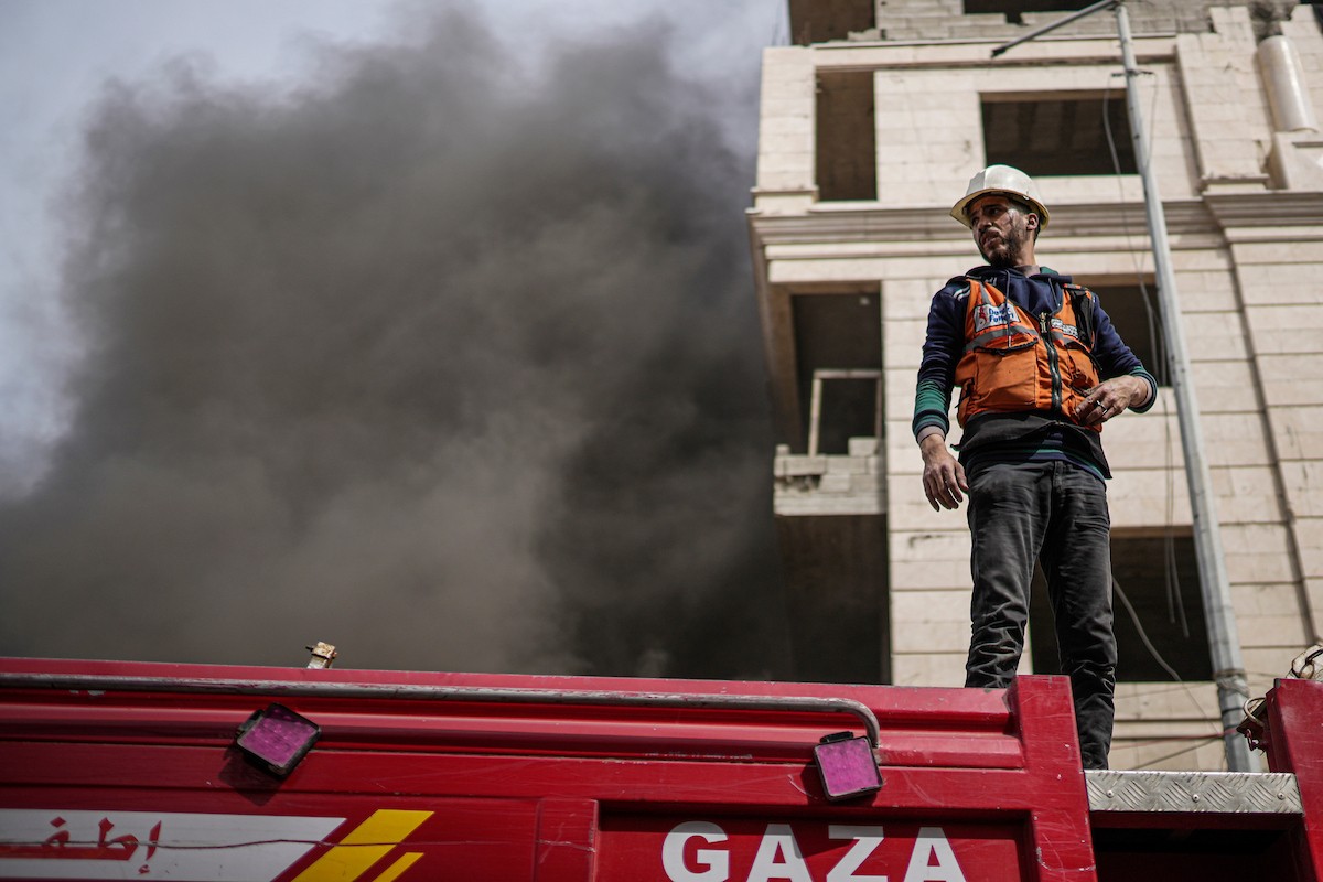 طواقم الدفاع المدني ومتطوعون من المواطنين أثناء محاولة إخماد حريق اندلع في مستودع تابع لمنظمة إغاثة في حي الرمال، غرب مدينة غزة، في 13 فبراير/شباط 2026. صورة: عمر أشتوي