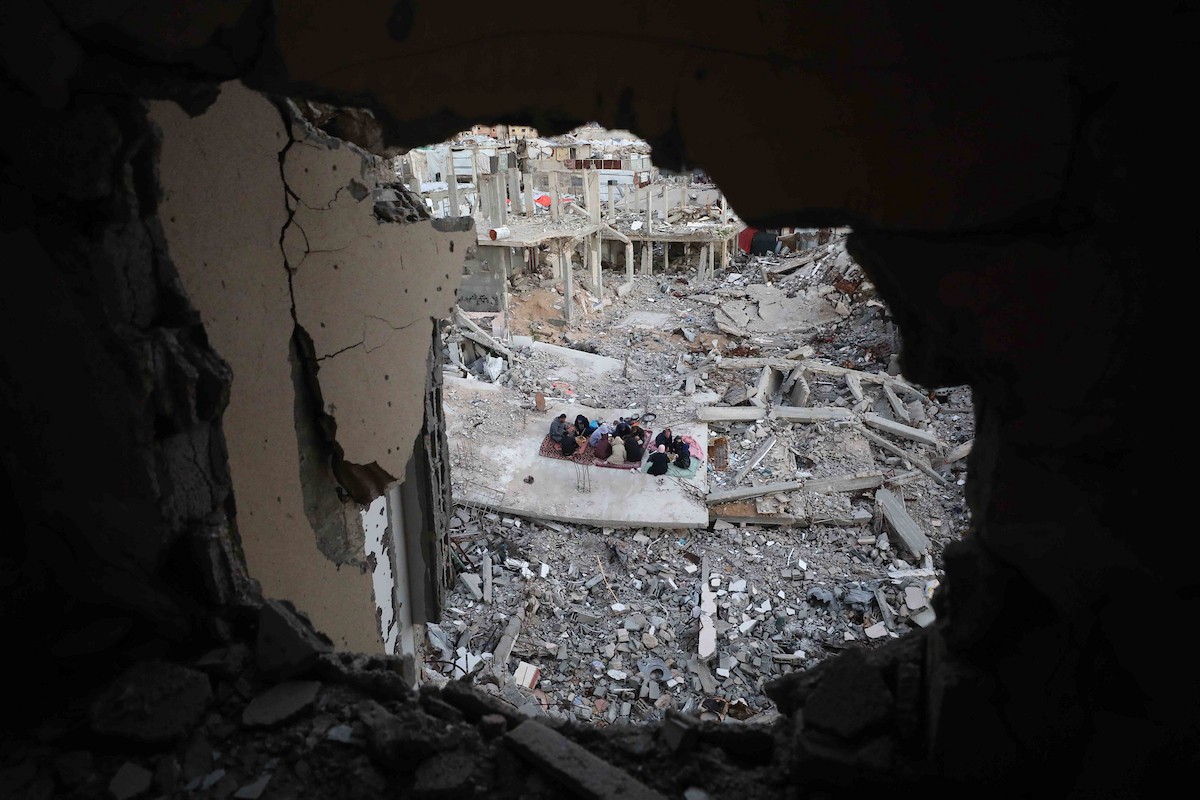 عائلة فلسطينية تتناول إفطارها خلال شهر رمضان على سطح منزلها الذي دمره قصف جوي إسرائيلي خلال حرب غزة في 27 فبراير/شباط 2026. صورة: عمر أشتوي