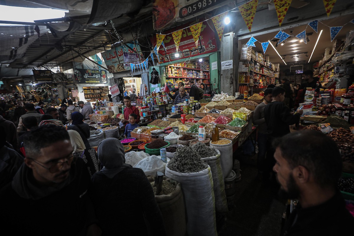 يتسوق الفلسطينيون في أول ليلة من شهر رمضان المبارك في سوق الزاوية، الواقع في قلب مدينة غزة والذي تضرر بشدة جراء الحرب الإسرائيلية. يعرض الباعة بضائعهم على أكشاك مزينة بالفوانيس والأضواء وأطعمة رمضان. مدينة غزة، 17 فبراير/شباط 2026. تصوير: عمر أشتوي