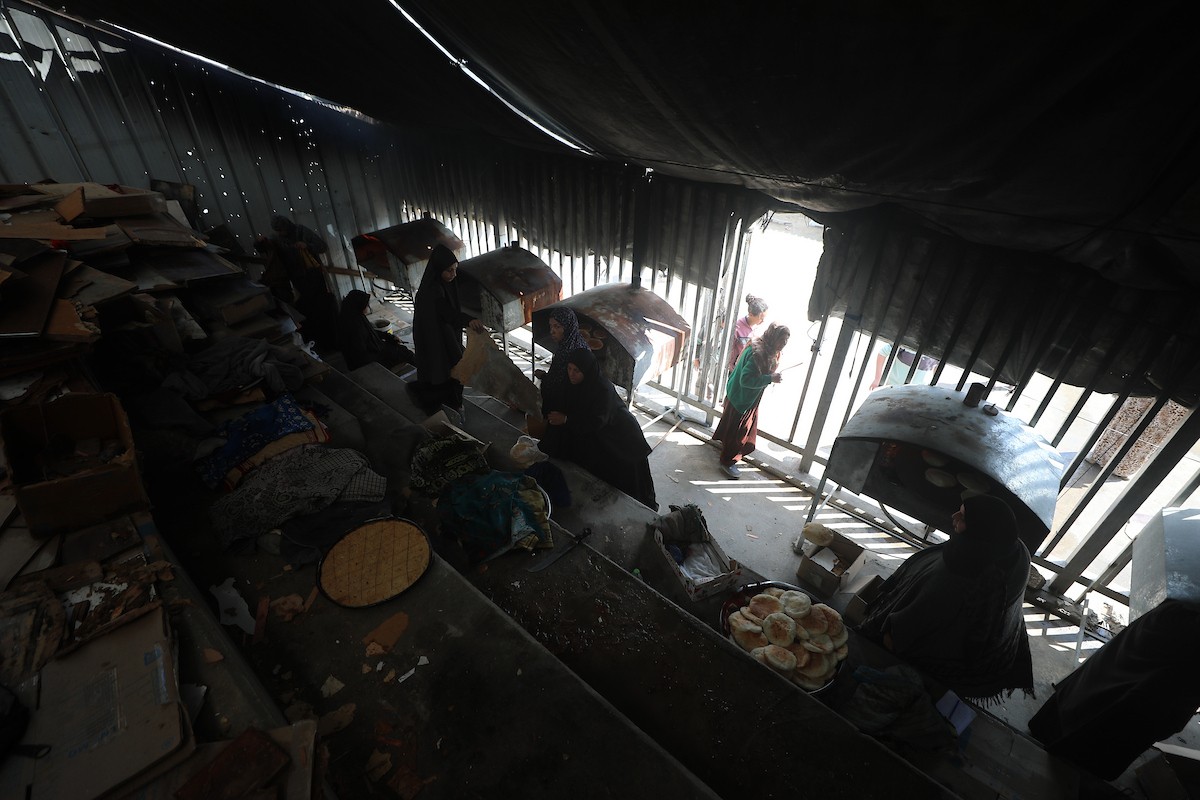 مجموعة من النساء يعملن داخل مخبز أُنشئ في مخيم اليرموك للاجئين بمدينة غزة، ضمن مبادرة إنسانية بالشراكة مع اللجنة الدولية للصليب الأحمر. تهدف المبادرة إلى تخفيف الأعباء المعيشية عن النساء النازحات، لا سيما خلال شهر رمضان. مدينة غزة، 25 فبراير/شباط 2026. تصوير: عمر أشتوي