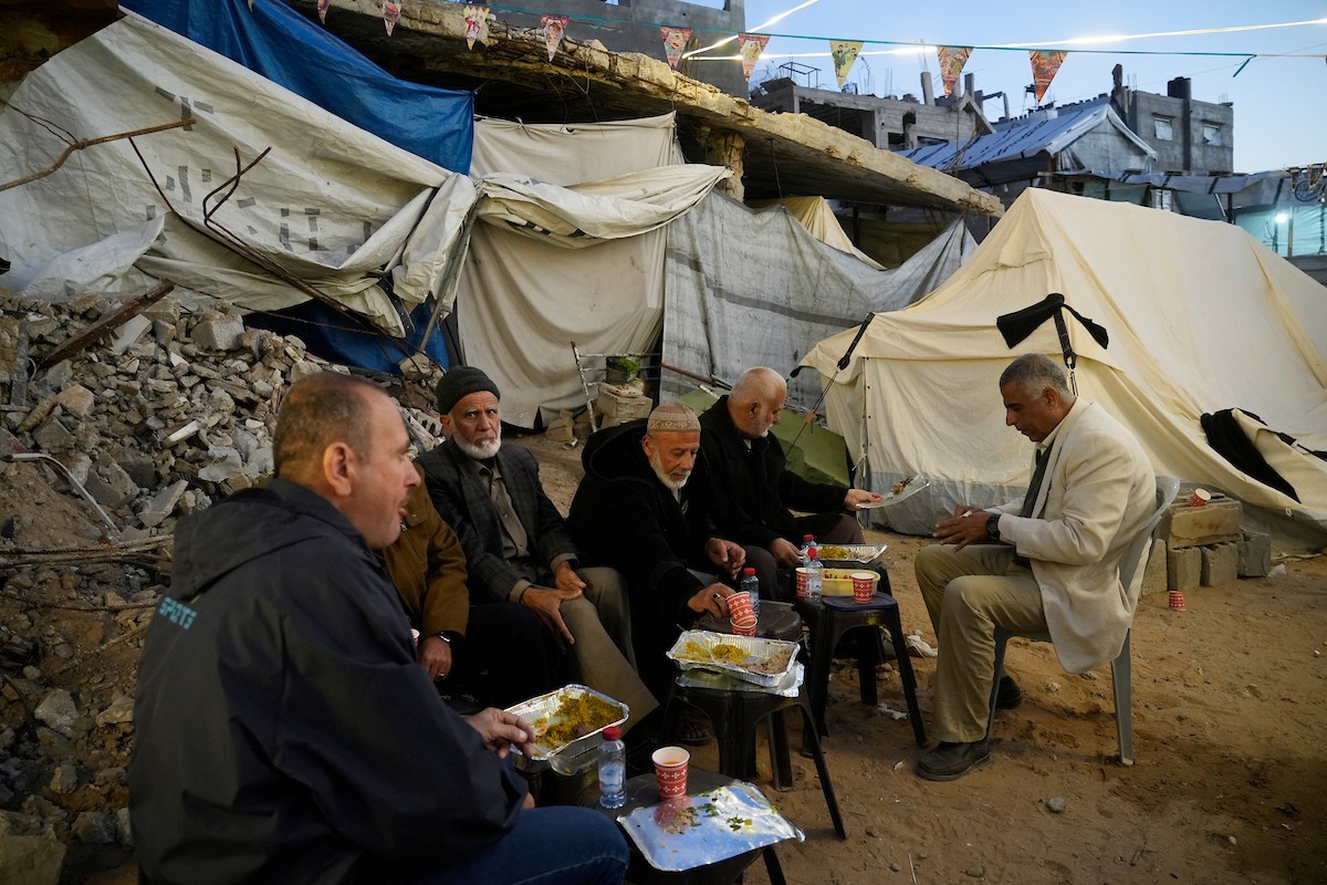 يتجمع الفلسطينيون بين المنازل المدمرة لتناول وجبة الإفطار معًا خلال شهر رمضان المبارك في شمال قطاع غزة، 22 فبراير/شباط 2026. صورة: عمر أشتوي