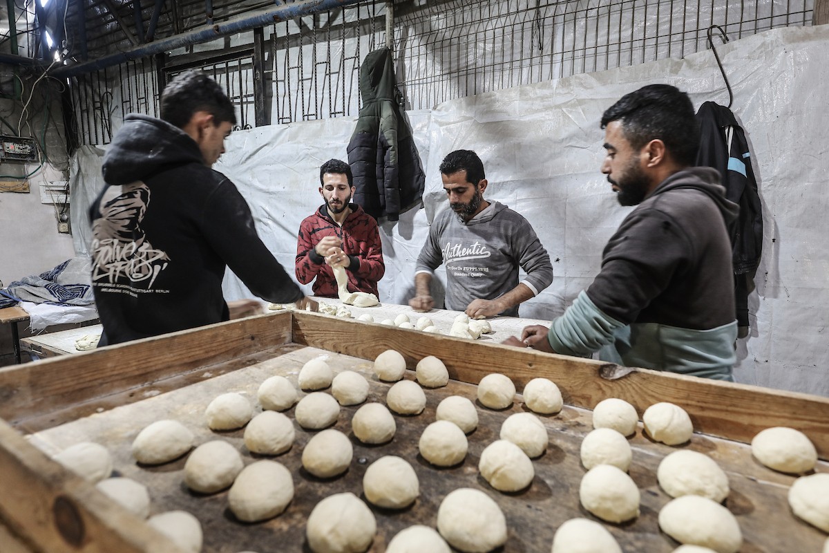 نساء فلسطينيات، زوجات شهداء الحرب، يُجهّزن الخبز لتوزيعه على العائلات النازحة والمحتاجة في مخيم البريج للاجئين وسط قطاع غزة خلال شهر رمضان، في مشهد يُجسّد روح التضامن والصمود في ظلّ الظروف الإنسانية الصعبة، فبراير/شباط 2026. تصوير: معز صالحي