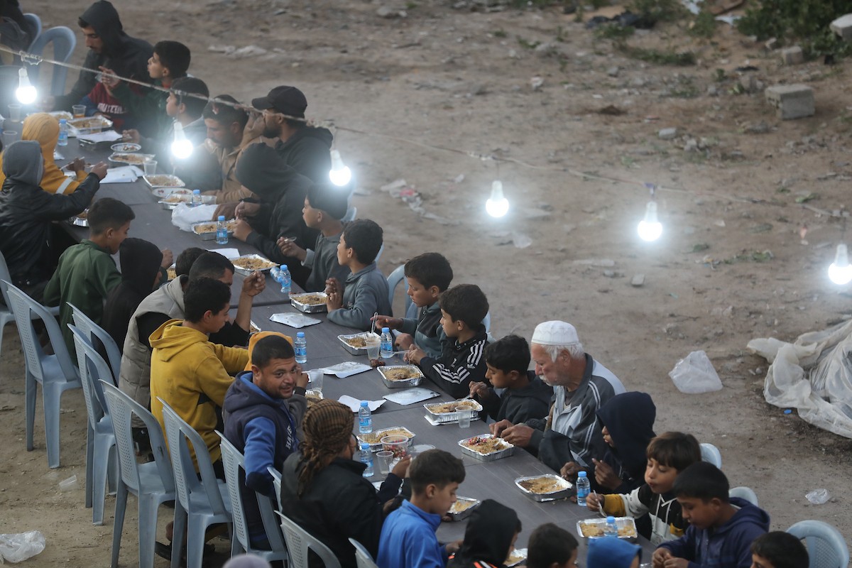 يتجمع فلسطينيون نازحون لتناول وجبة الإفطار وسط أنقاض المباني المدمرة في مدينة غزة، خلال شهر رمضان المبارك، في 25 فبراير/شباط 2026. صورة: عمر أشتوي