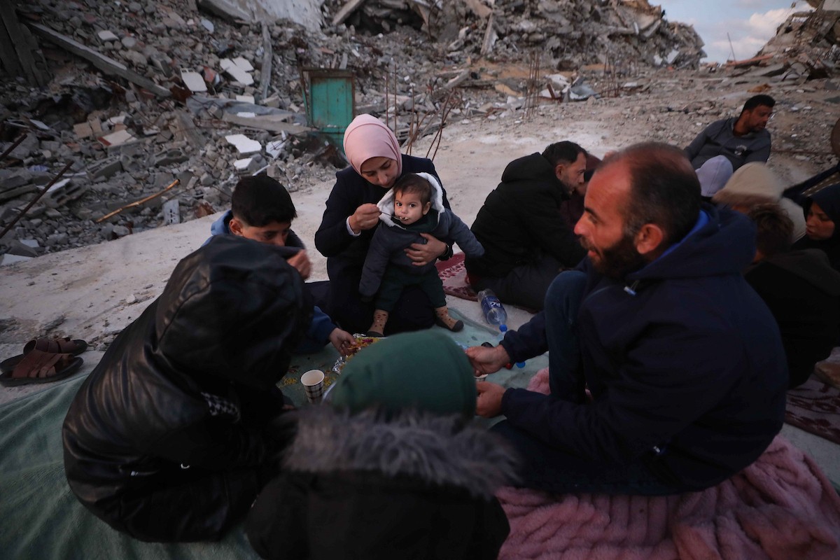 عائلة فلسطينية تتناول إفطارها خلال شهر رمضان على سطح منزلها الذي دمره قصف جوي إسرائيلي خلال حرب غزة في 27 فبراير/شباط 2026. صورة: عمر أشتوي