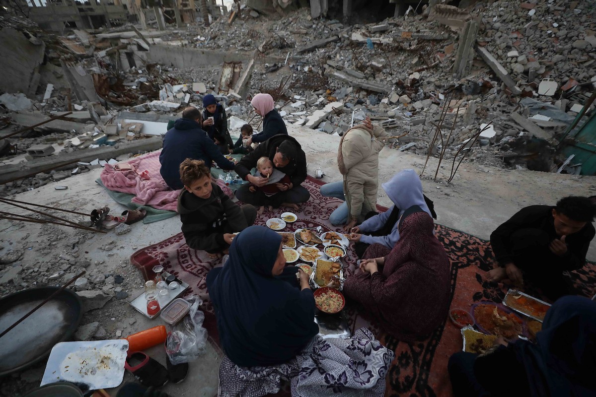 عائلة فلسطينية تتناول إفطارها خلال شهر رمضان على سطح منزلها الذي دمره قصف جوي إسرائيلي خلال حرب غزة في 27 فبراير/شباط 2026. صورة: عمر أشتوي