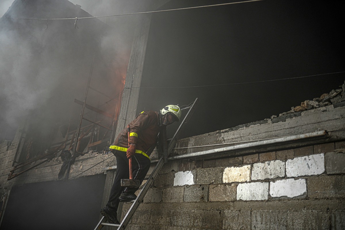 طواقم الدفاع المدني ومتطوعون من المواطنين أثناء محاولة إخماد حريق اندلع في مستودع تابع لمنظمة إغاثة في حي الرمال، غرب مدينة غزة، في 13 فبراير/شباط 2026. صورة: عمر أشتوي