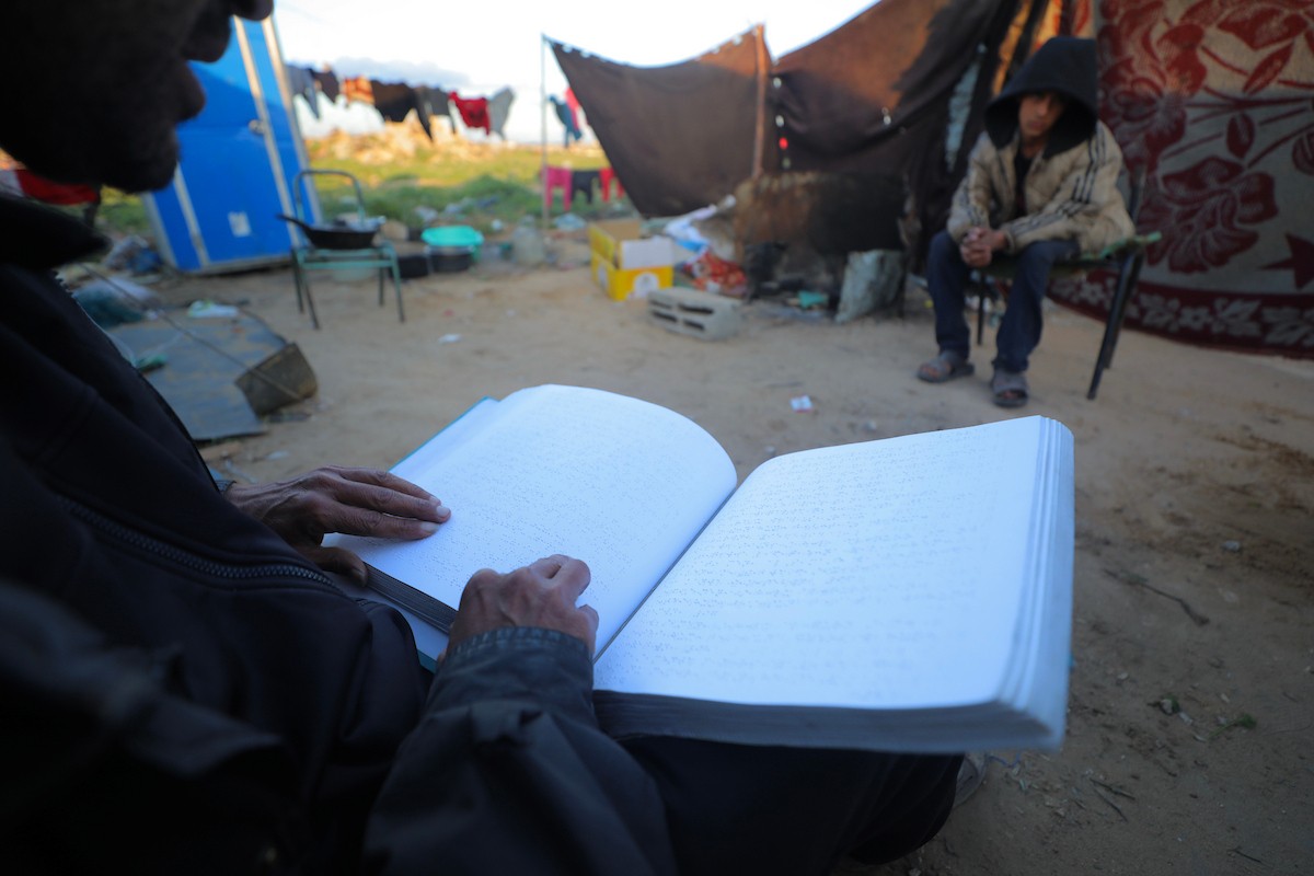 عائلة فلسطينية كفيفة تتناول وجبة الإفطار خارج خيمتها في مخيم بوسط قطاع غزة خلال شهر رمضان