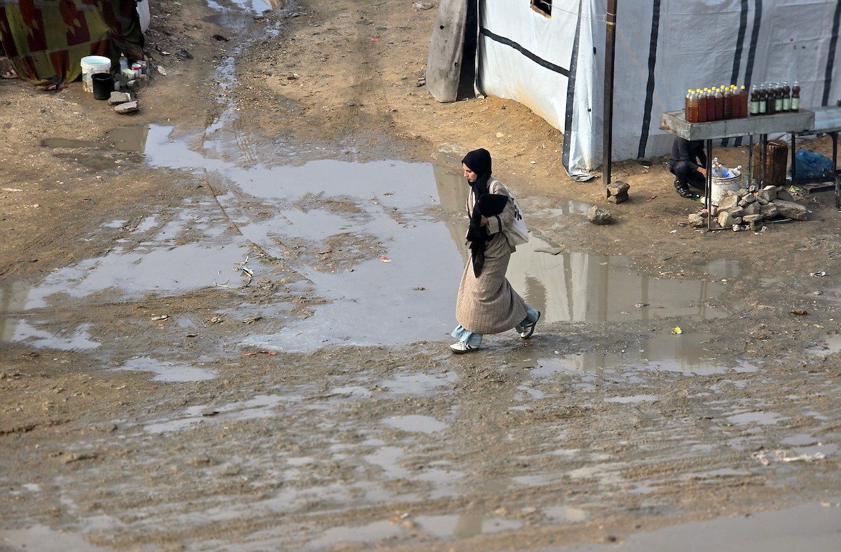 يحاول الفلسطينيون التنقل بعد أن غمرت مياه الأمطار الشوارع وخيام النازحين في خان يونس، جنوب قطاع غزة، في 24 فبراير/شباط 2026. وقد دُمرت البنية التحتية في قطاع غزة على نطاق واسع جراء الحرب والهجمات الإسرائيلية. (صورة: طارق محمد)